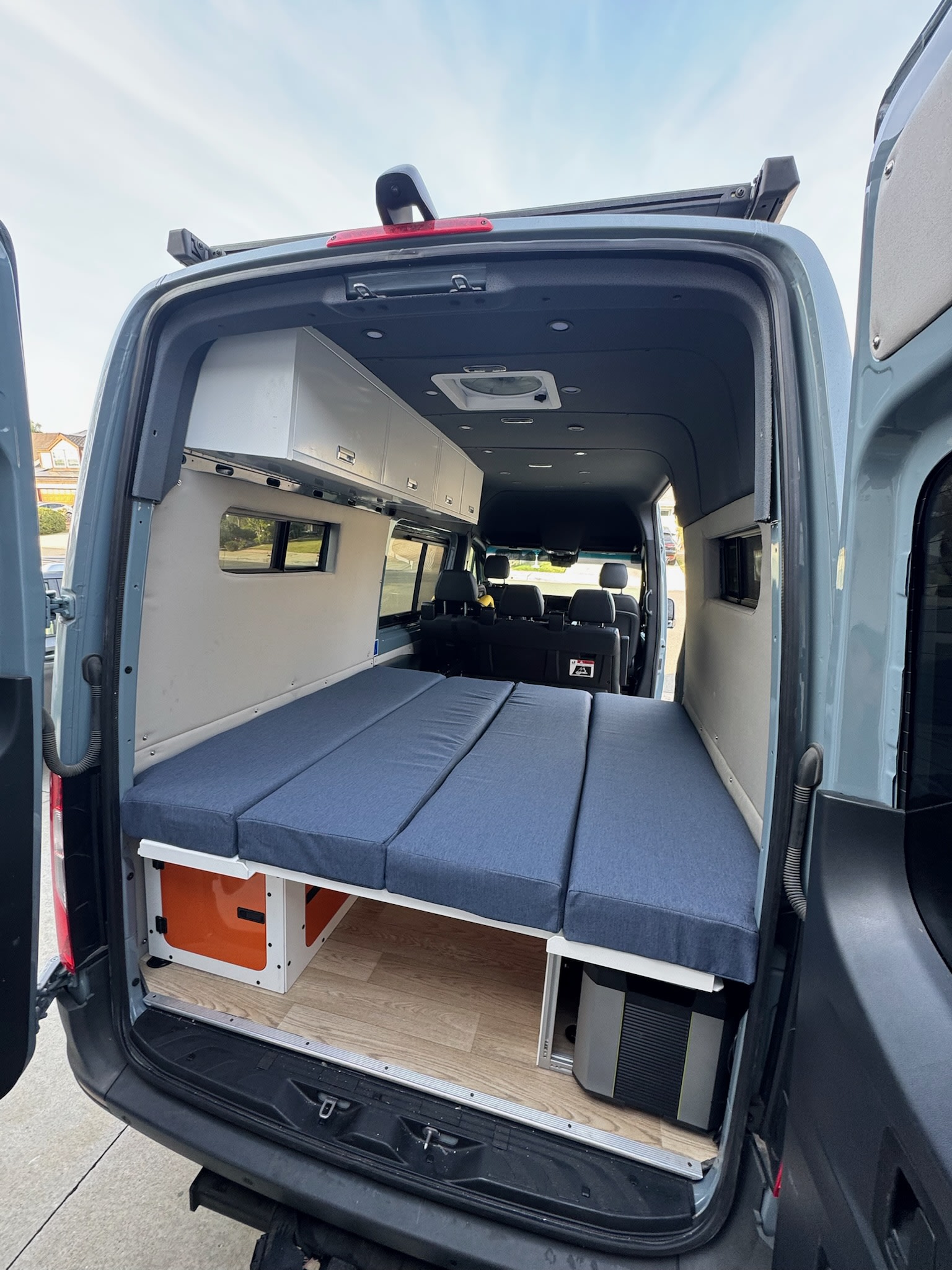 Spacious RV rental camper van interior with modular bed, overhead storage, and under-bed gear.. Mercedes Sprinter 2021