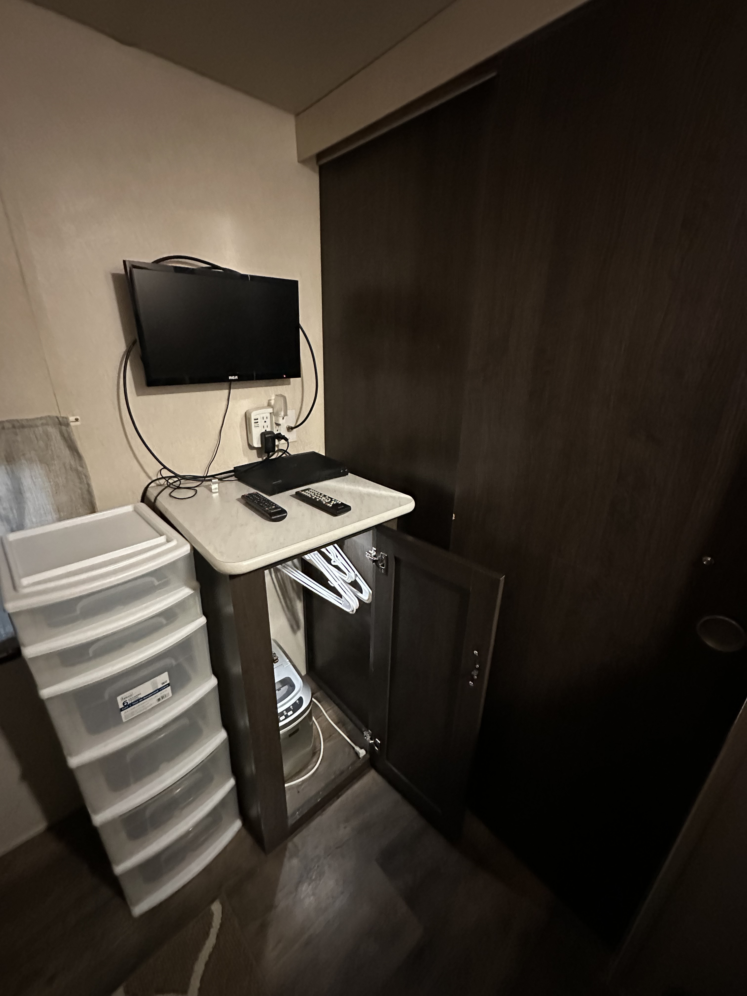 RV rental: Compact living space with wall-mounted TV, plastic storage drawers, and cabinet with hangers.. Forest River Wildwood X-Lite 2019