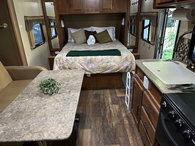 Inside this RV rental, find a comfortable bed, compact kitchen with a sink & stove, and a dining area.. Forest River Surveyor Cadet 2014