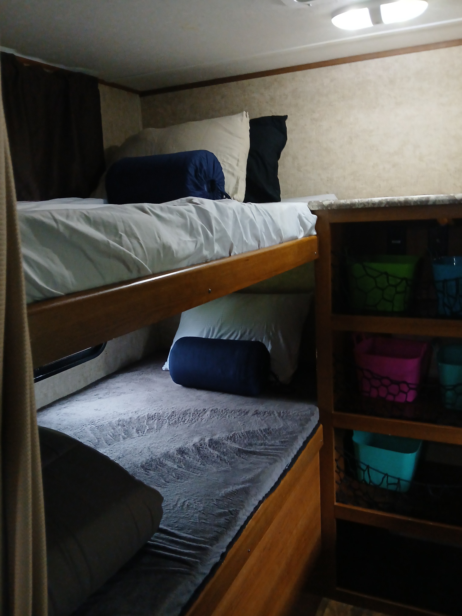 Inside an **rv rental**: two bunk beds with bedding & pillows, plus a side shelving unit with colorful storage bins.. Forest River Tracer Air 2016