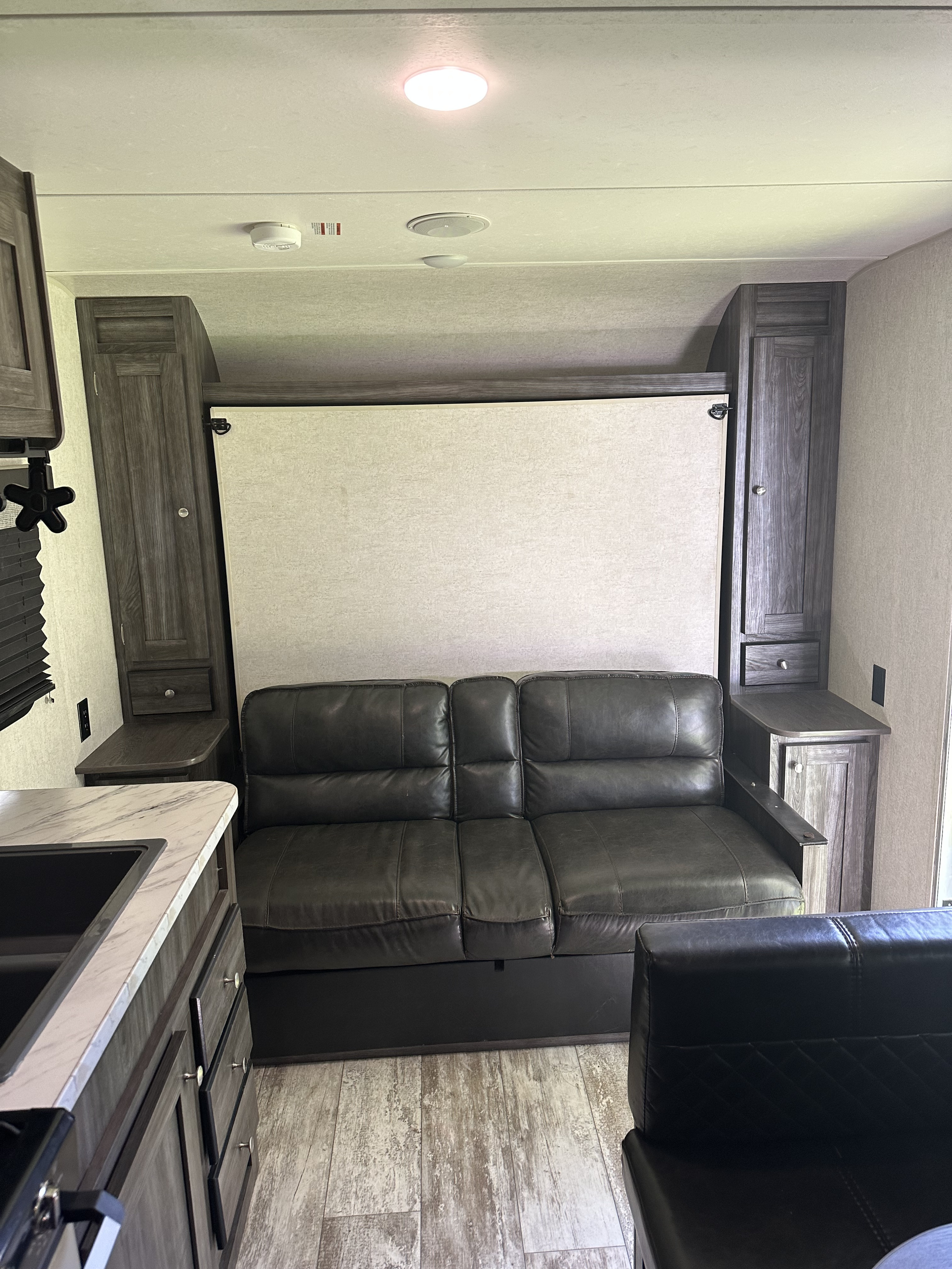 Cozy **RV rental** interior: a dark leather sofa, cleverly hidden Murphy bed, and kitchen counter for your travels.. Highland Ridge RV Open Range 2019