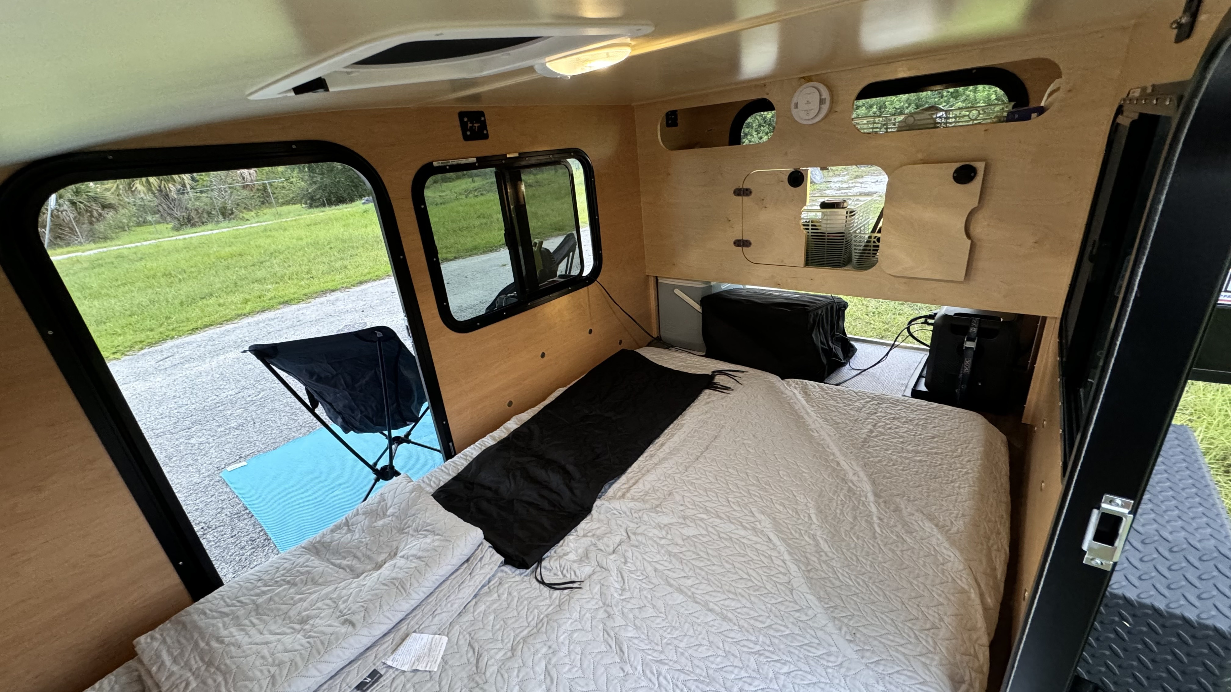 An RV rental's inviting interior: a comfortable bed, large windows viewing nature, and clever built-in storage.. Hiker Trailer Highway Deluxe 2025