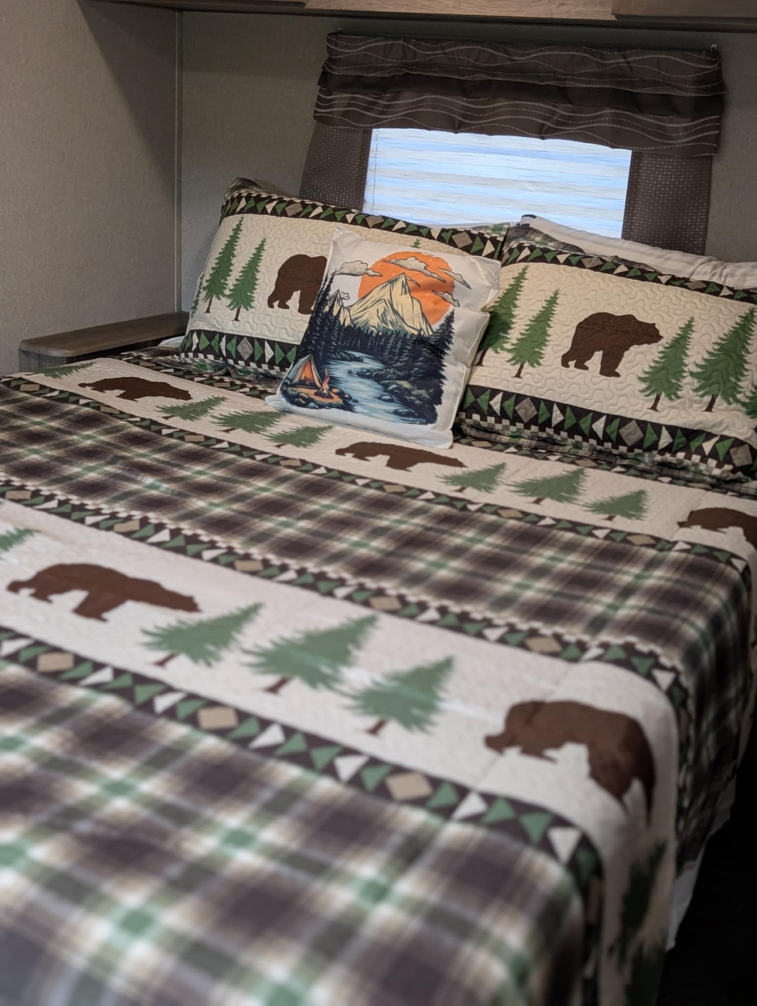 Comfortable RV rental bed featuring rustic bear and tree bedding, plus a scenic mountain pillow.. Palomino Puma 32RBFQ 2019