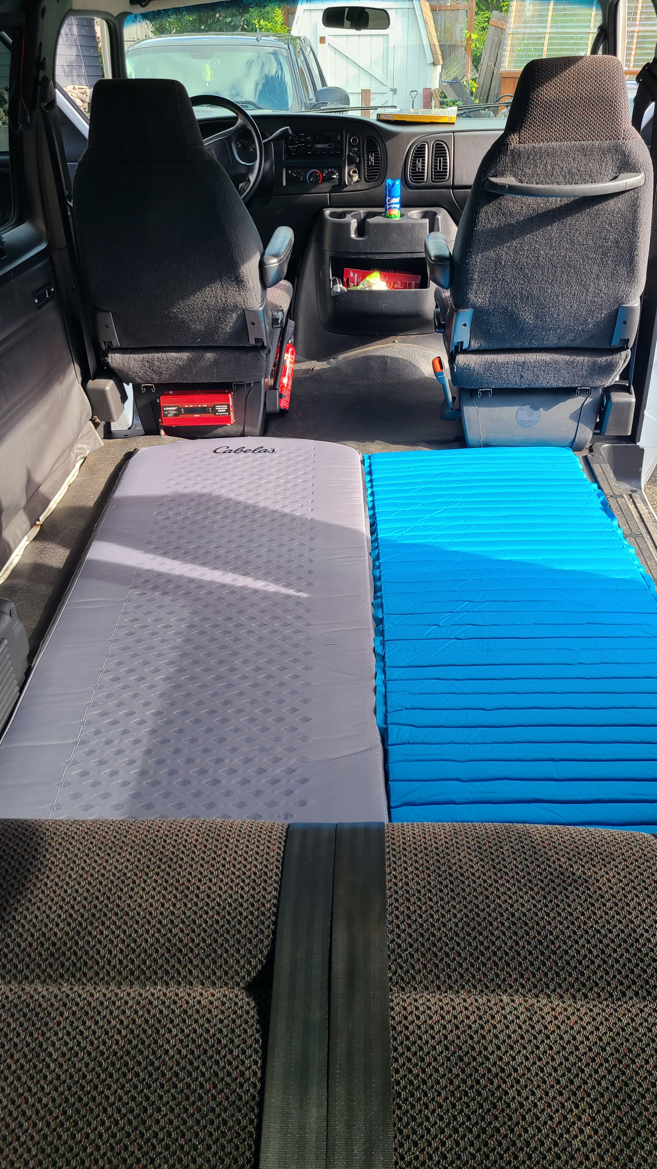 Van interior converted for travel, featuring dual sleeping pads. Ideal RV rental choice!. Dodge Ram 3500 2002