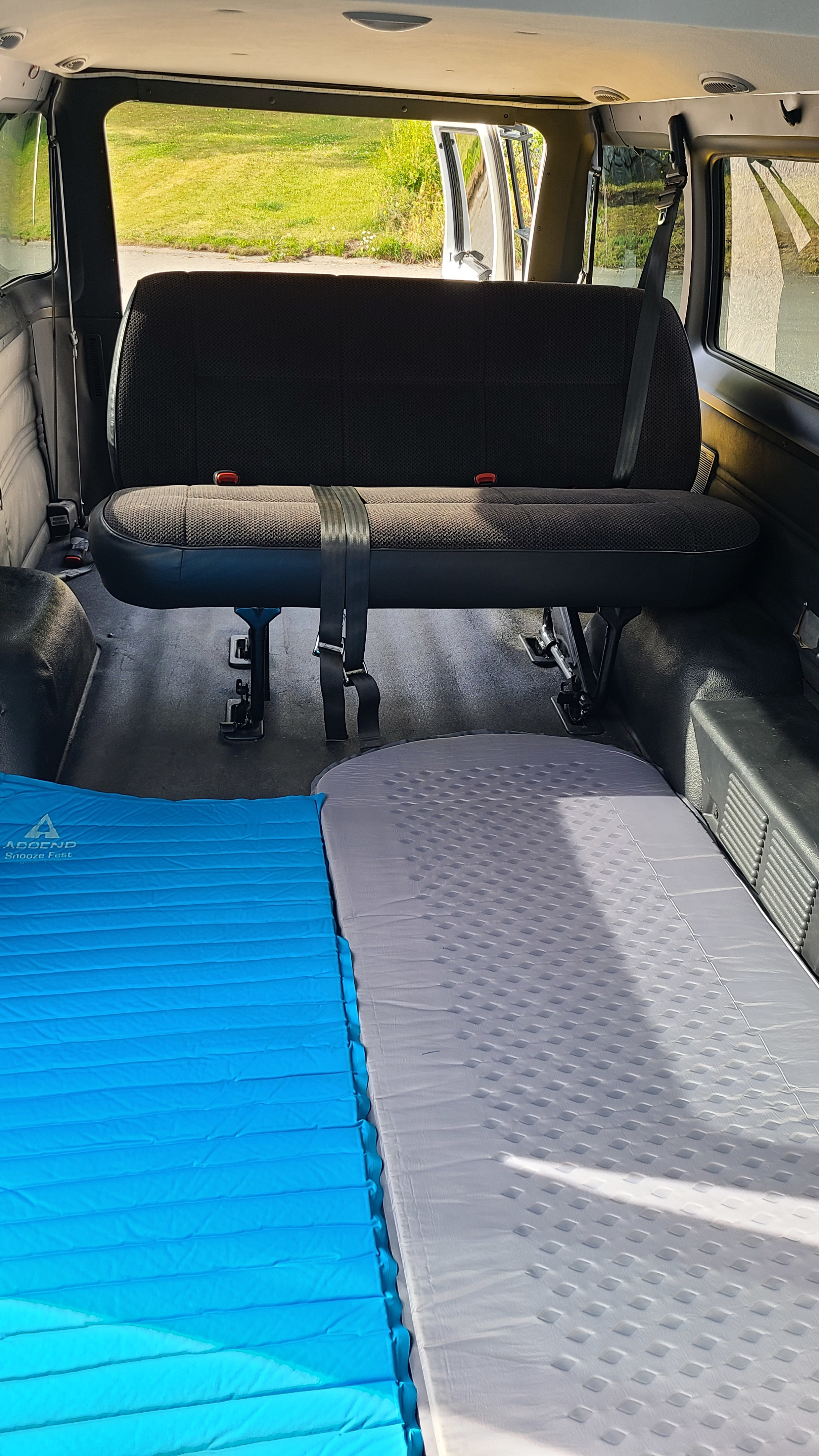 RV rental interior featuring a bench seat & two laid-out sleeping pads, ideal for comfortable van camping.. Dodge Ram 3500 2002
