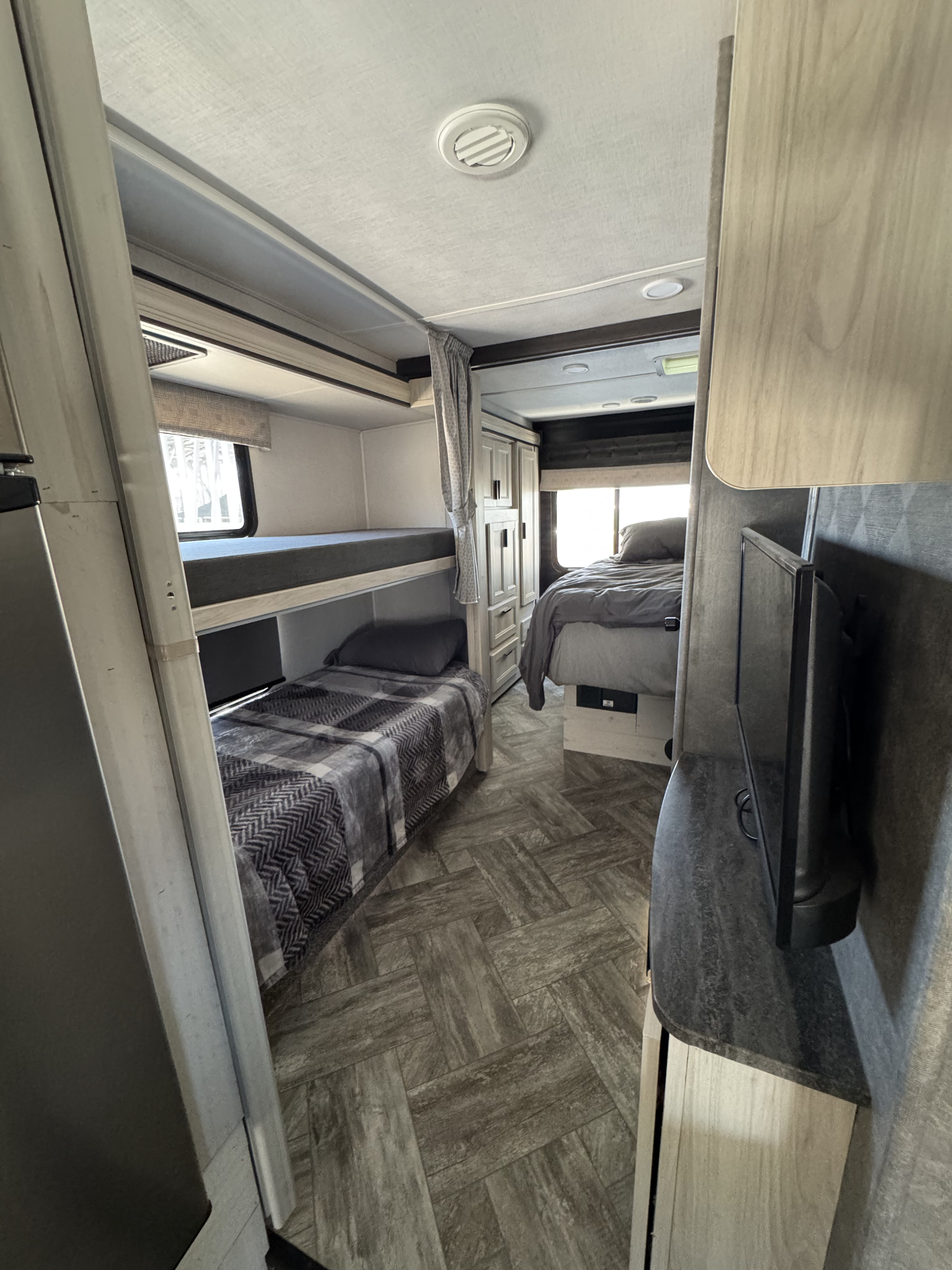 This RV rental interior features bunk beds, a master bedroom with a TV, and stylish flooring, ensuring comfort for your journey.. Forest River Sunseeker LE 2022