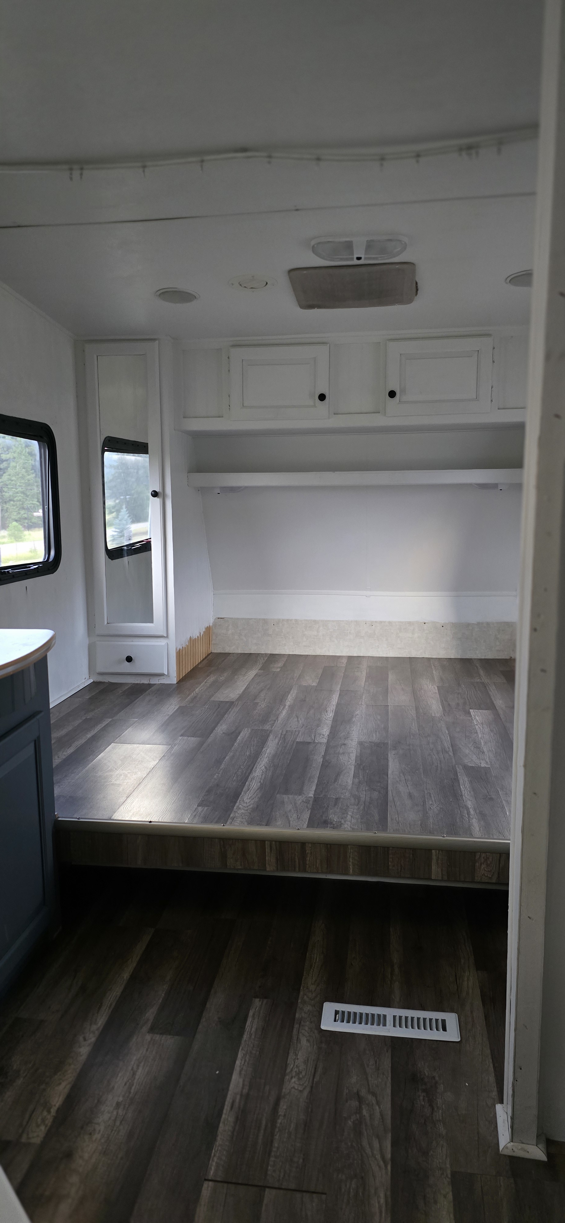 Bright RV rental interior showcasing new wood-look flooring, white cabinets, and a comfortable sleeping area.. R-Vision Trail-Lite Trail-Bay 2005