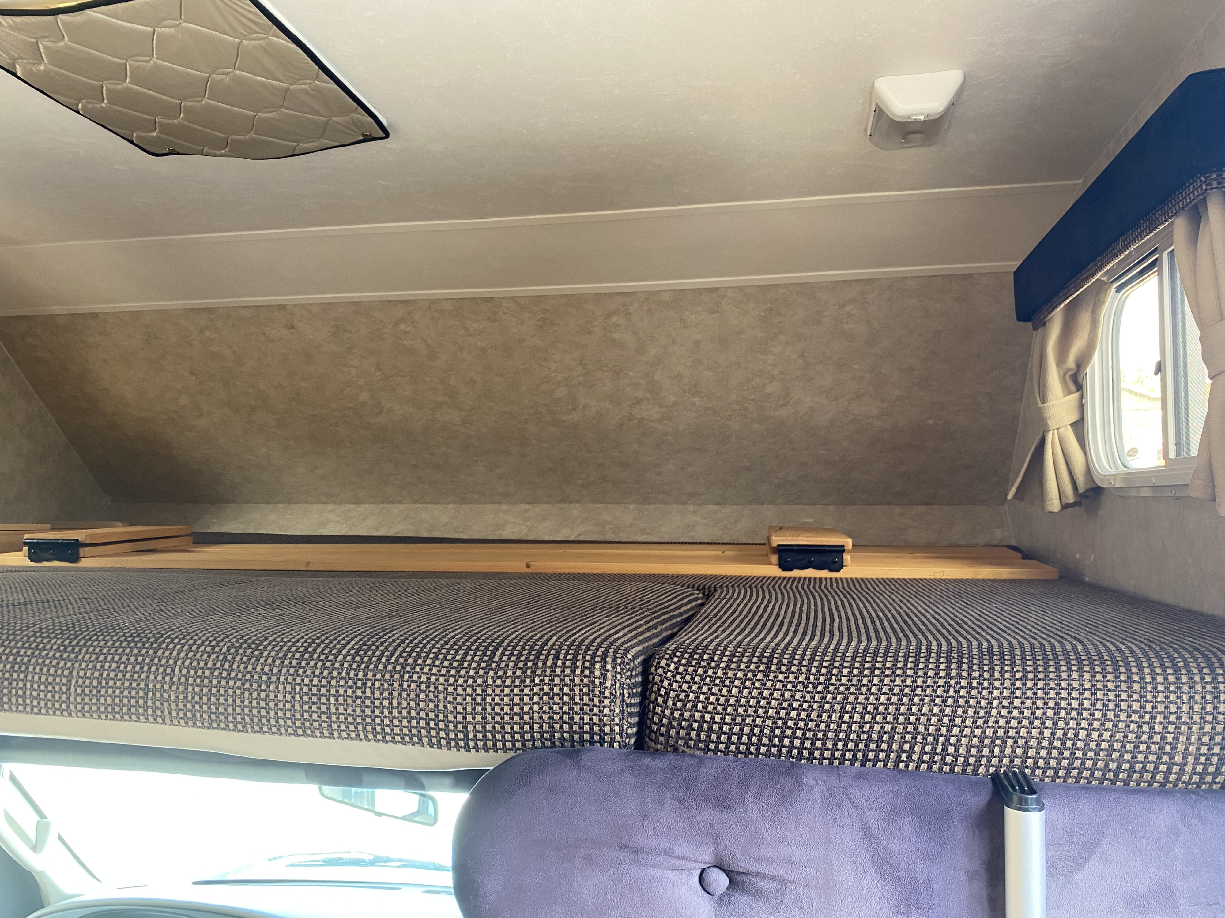 Interior view of an RV rental's cab-over bunk, featuring a bed, wooden slats, a window, and ceiling light.. Adventurer Adventurer Motorhome 2008