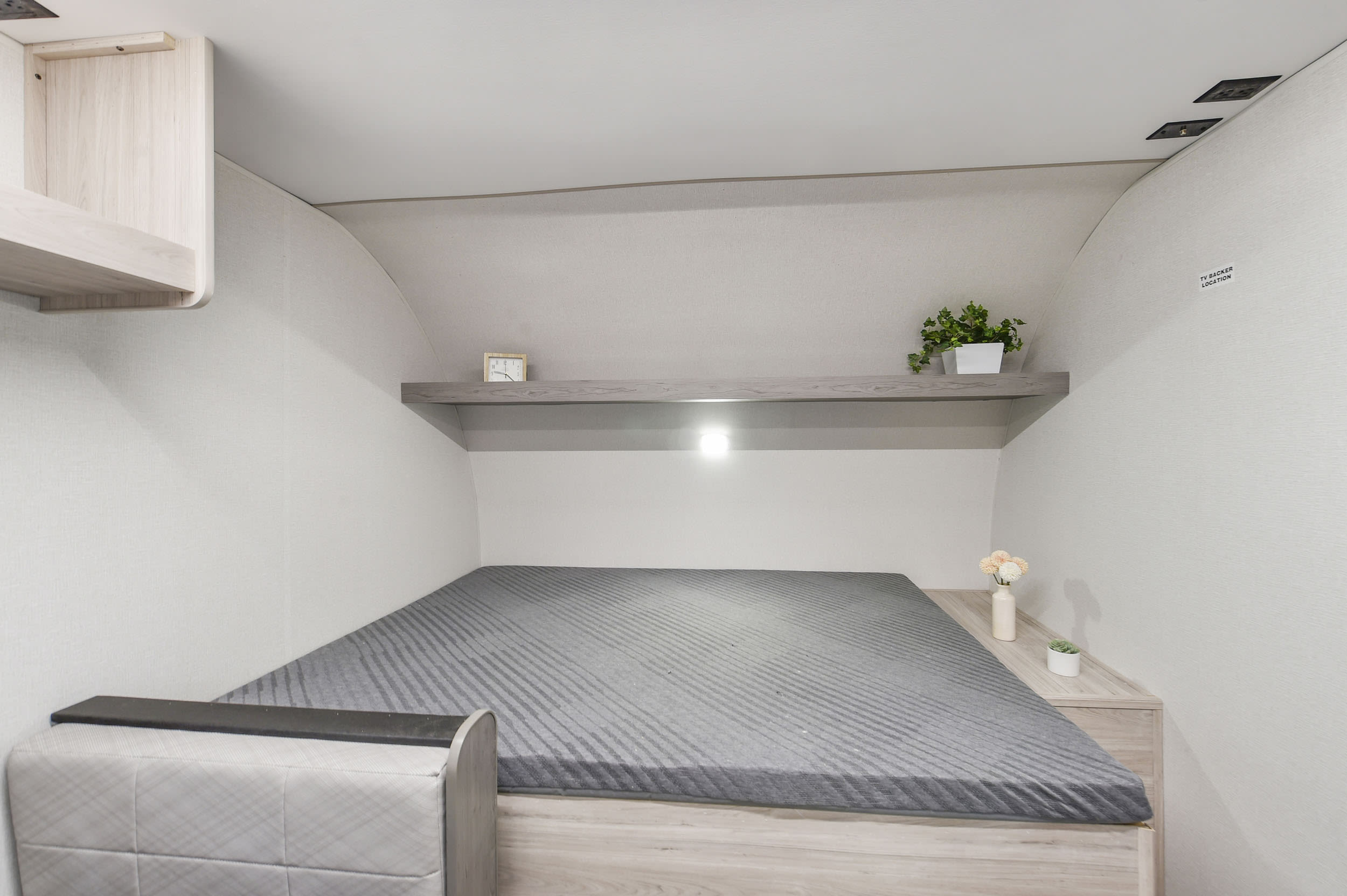 Relax in this compact RV rental bedroom, featuring a comfortable bed, overhead shelf with light, and smart storage. Ready for travel.. Heartland RVs Mallard 2025