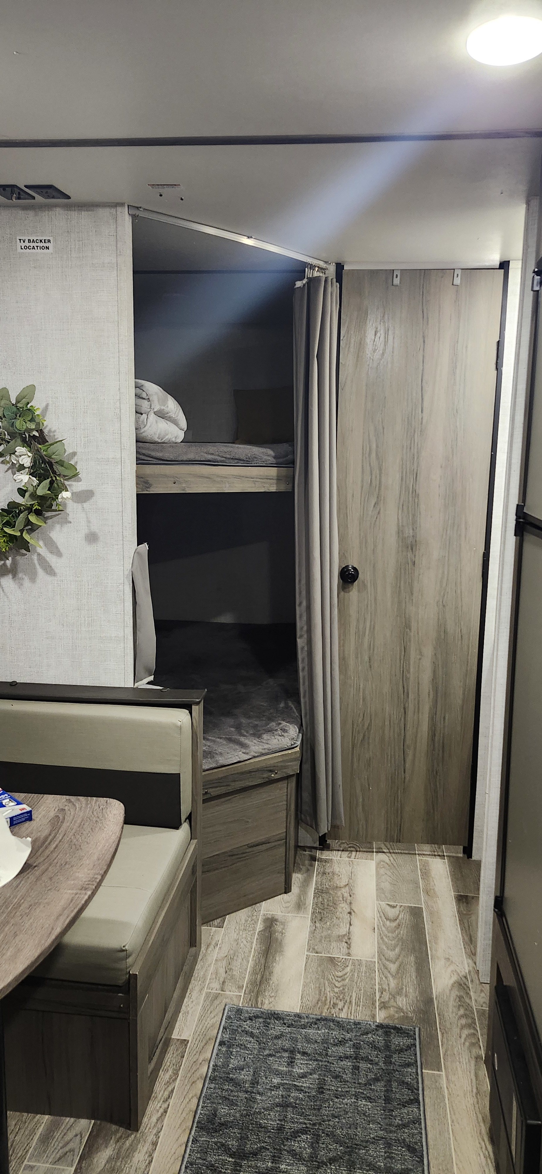 RV rental interior: cozy bunk beds with privacy curtain, practical dinette, and wood-look flooring.. Gulf Stream Enlighten 2021