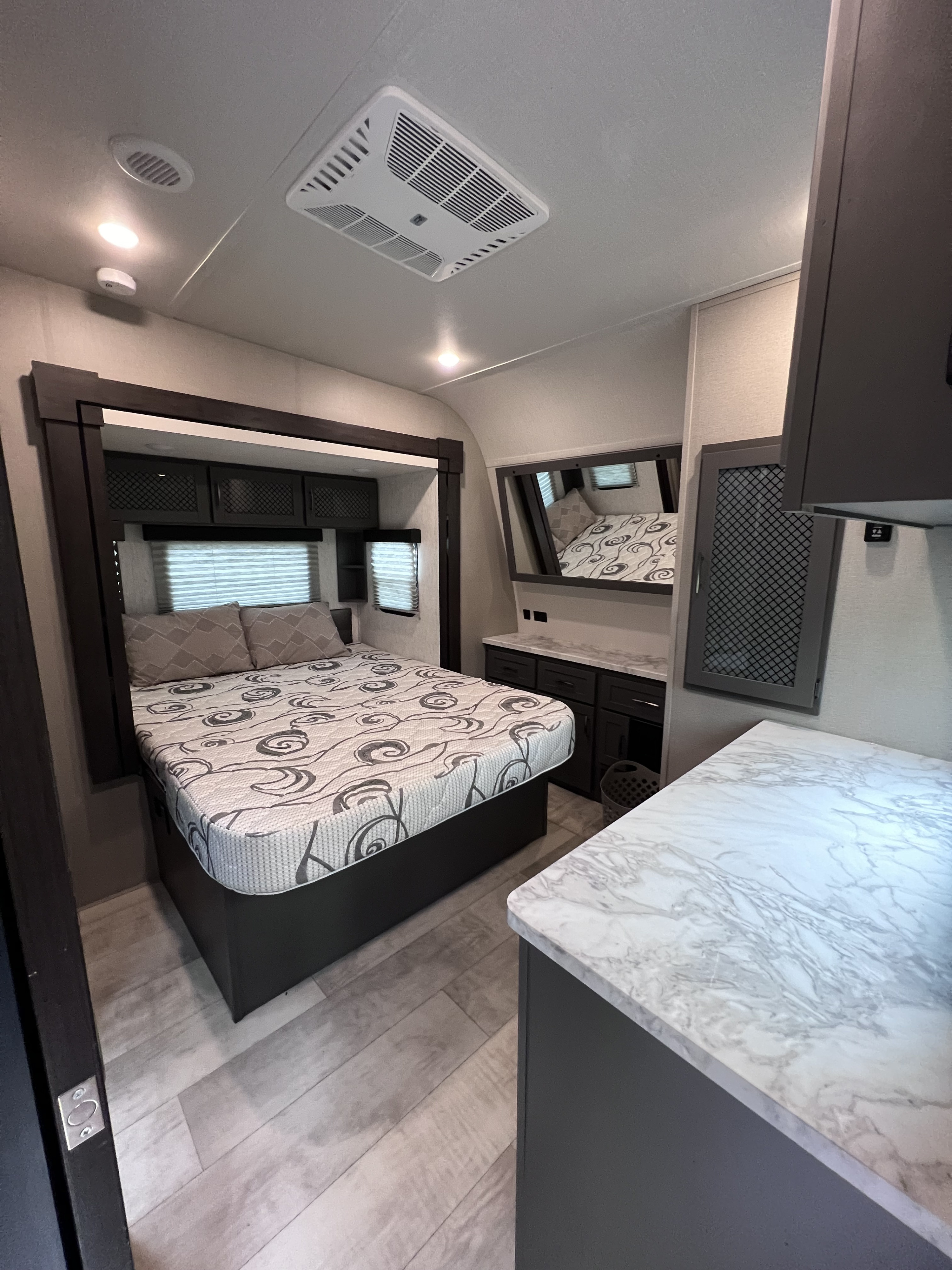 Modern RV rental bedroom, featuring a comfortable bed, overhead storage, and clean aesthetic. Your cozy home on wheels.. Grand Design Momentum 2022