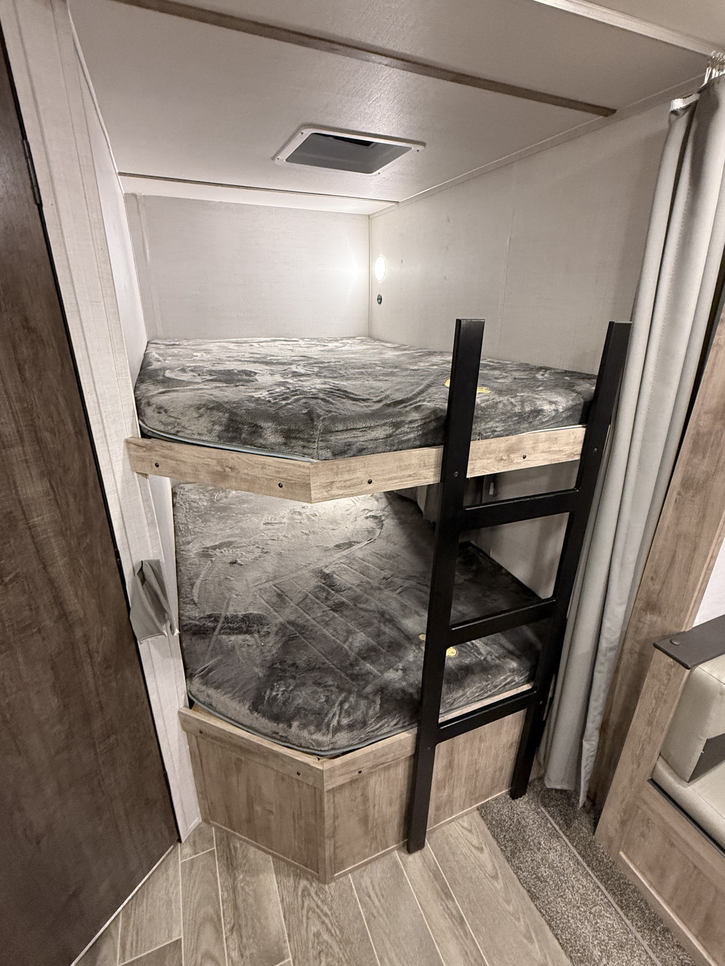 Cozy bunk beds in an RV rental, featuring a ladder, lights, and a ceiling vent. Ideal for small spaces.. Gulf Stream Ameri-Lite 2023