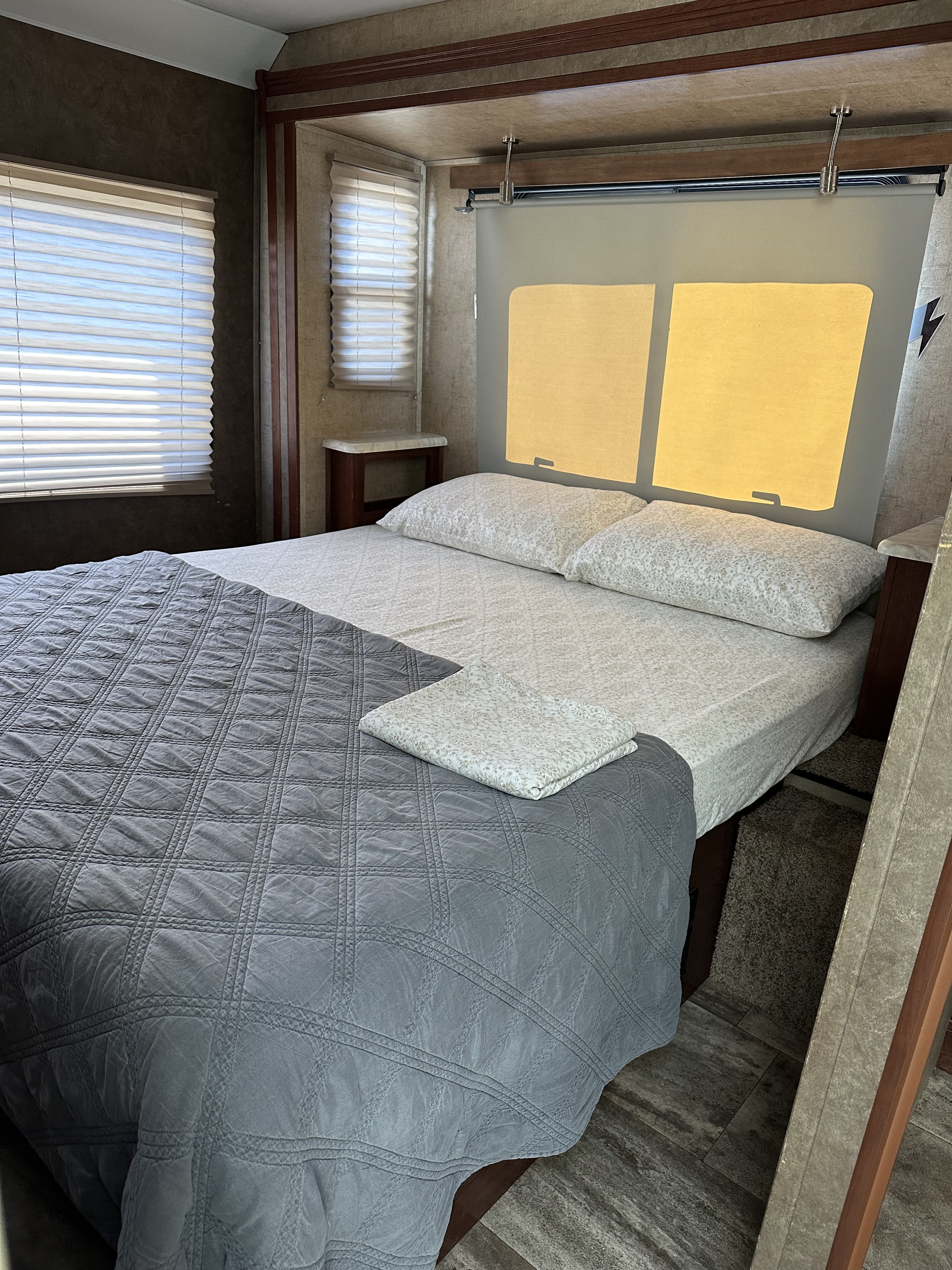 RV rental bedroom with a cozy bed, gray comforter, patterned sheets, window blinds, and glowing headboard.. Forest River Forester 2861DS 2016
