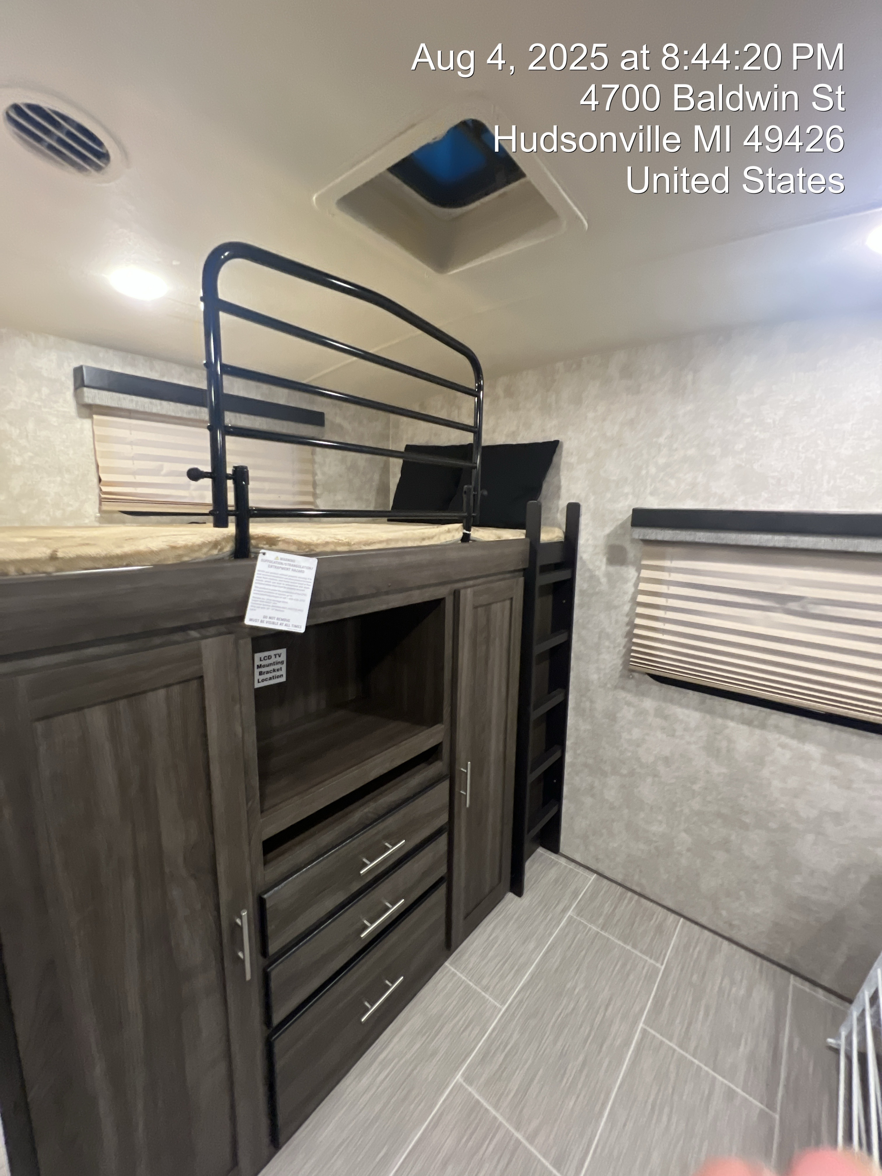 Modern RV rental interior: bunk beds with safety rail, ladder, and ample storage below. Features windows with blinds and a tiled floor.. Jayco highland Ridge 2019