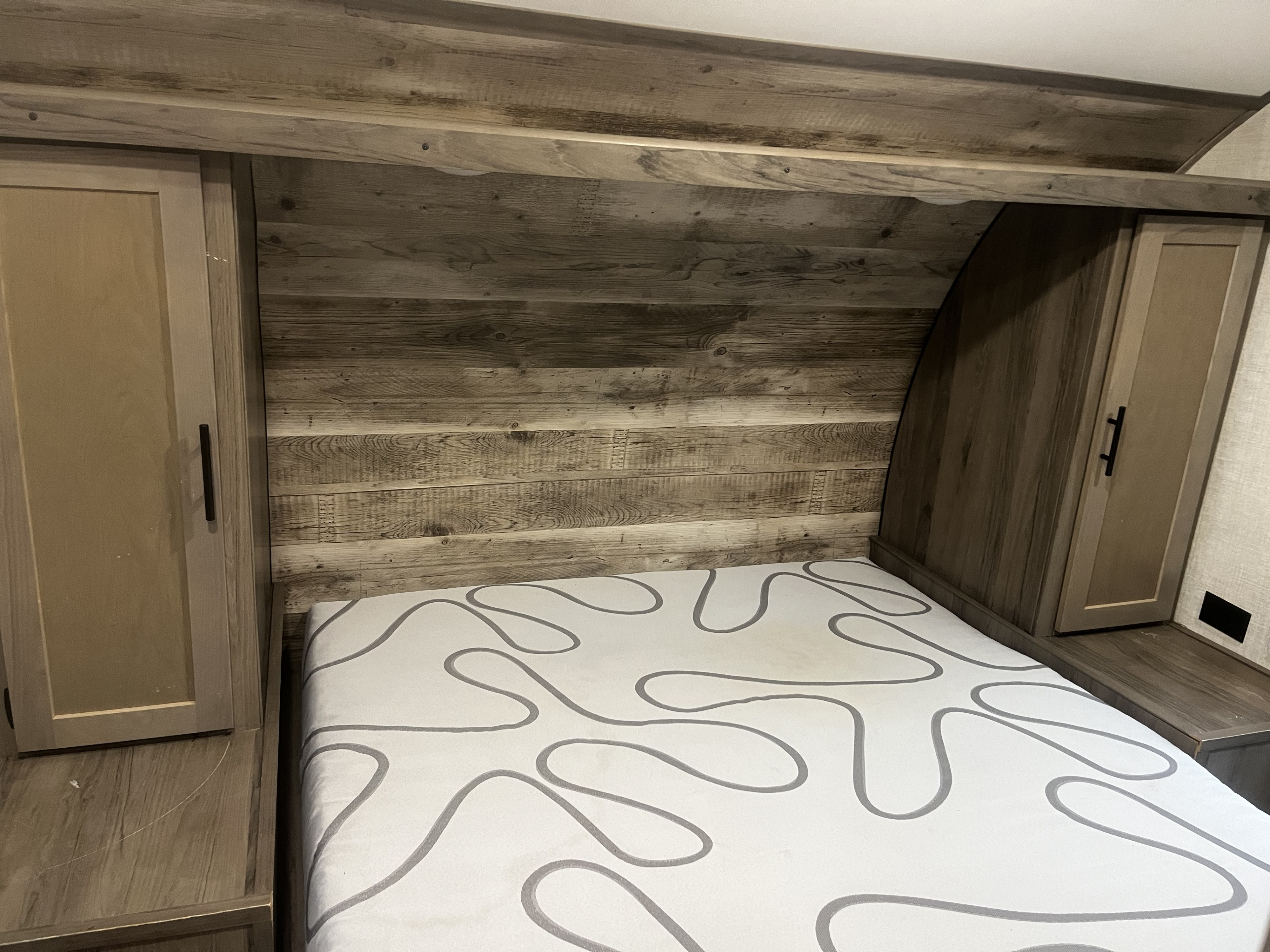 Spacious RV rental bedroom with a headboard made of wood-look panels, side cabinets, and a patterned mattress.. Gulf Stream Innsbruck 2022