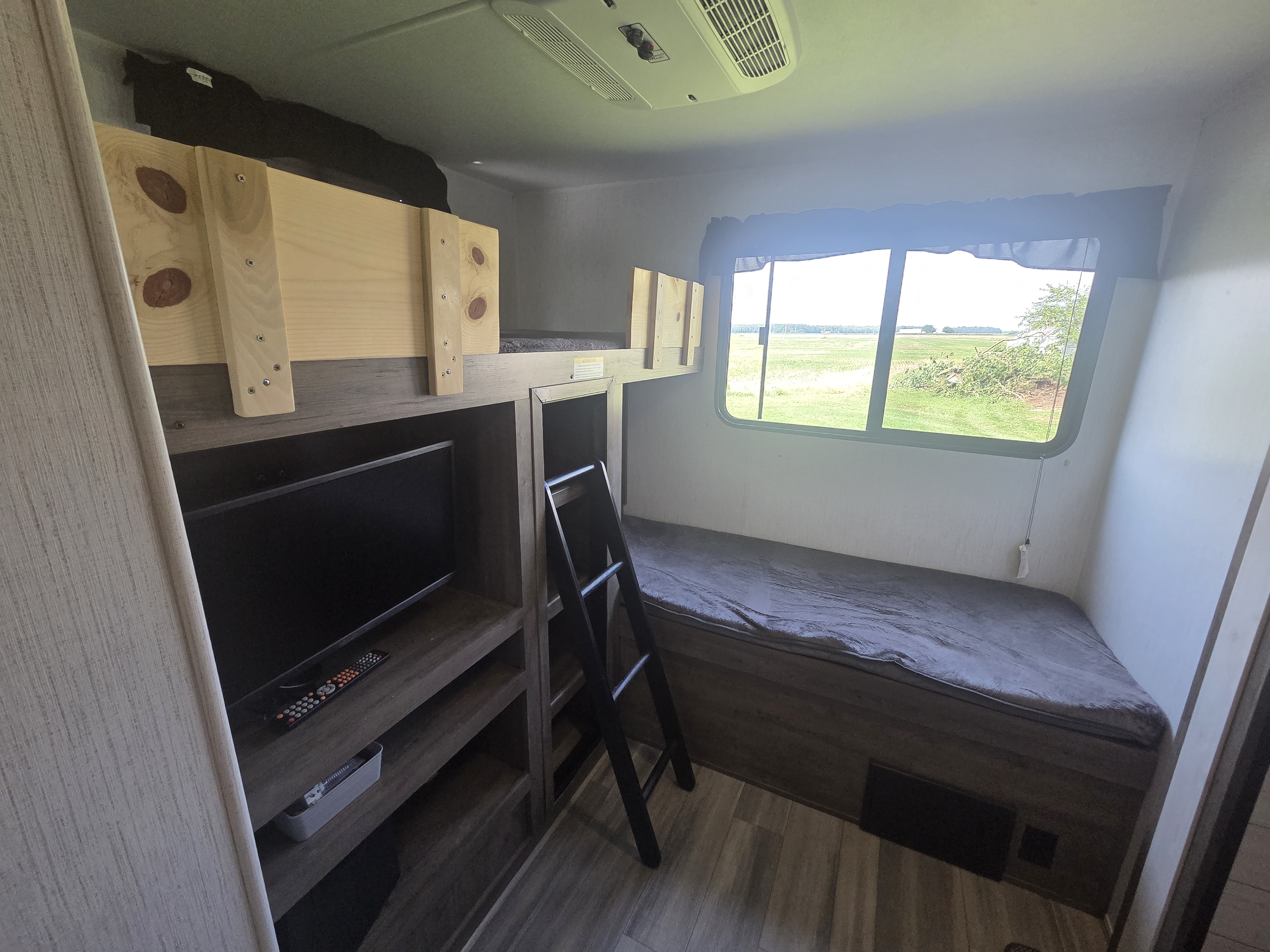 RV rental bunk room: comfy beds, TV, and a beautiful outdoor view from the large window. Perfect for family adventures.. Heartland RVs Pioneer 2023