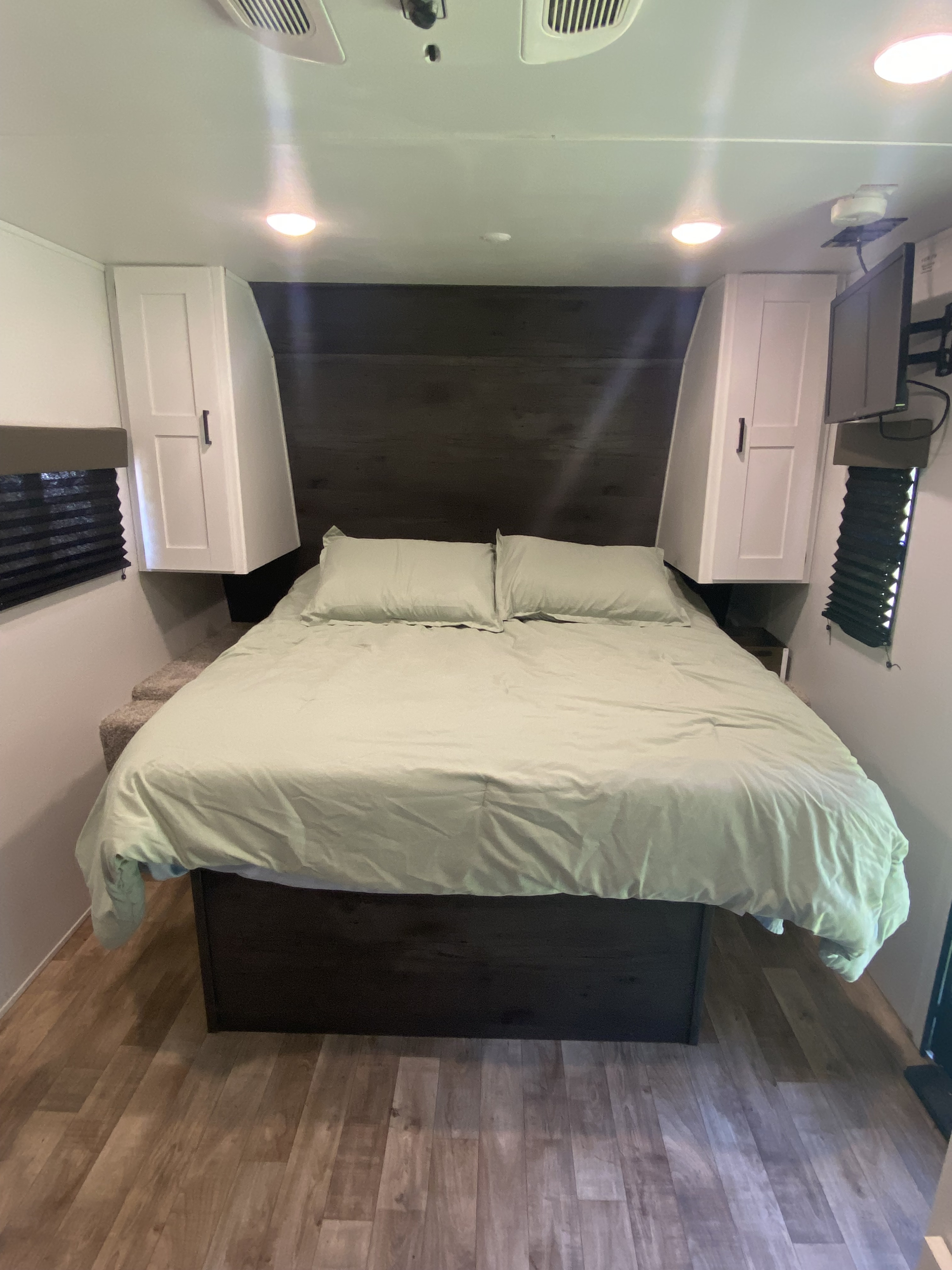 Spacious RV rental bedroom with a comfortable bed, light green bedding, and ample overhead storage.. Keystone RV Hideout 2022