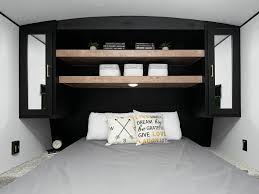 This inviting RV rental bedroom features a comfy bed and modern black built-in storage with wooden shelves, ideal for travel.. Keystone RV Springdale 2022