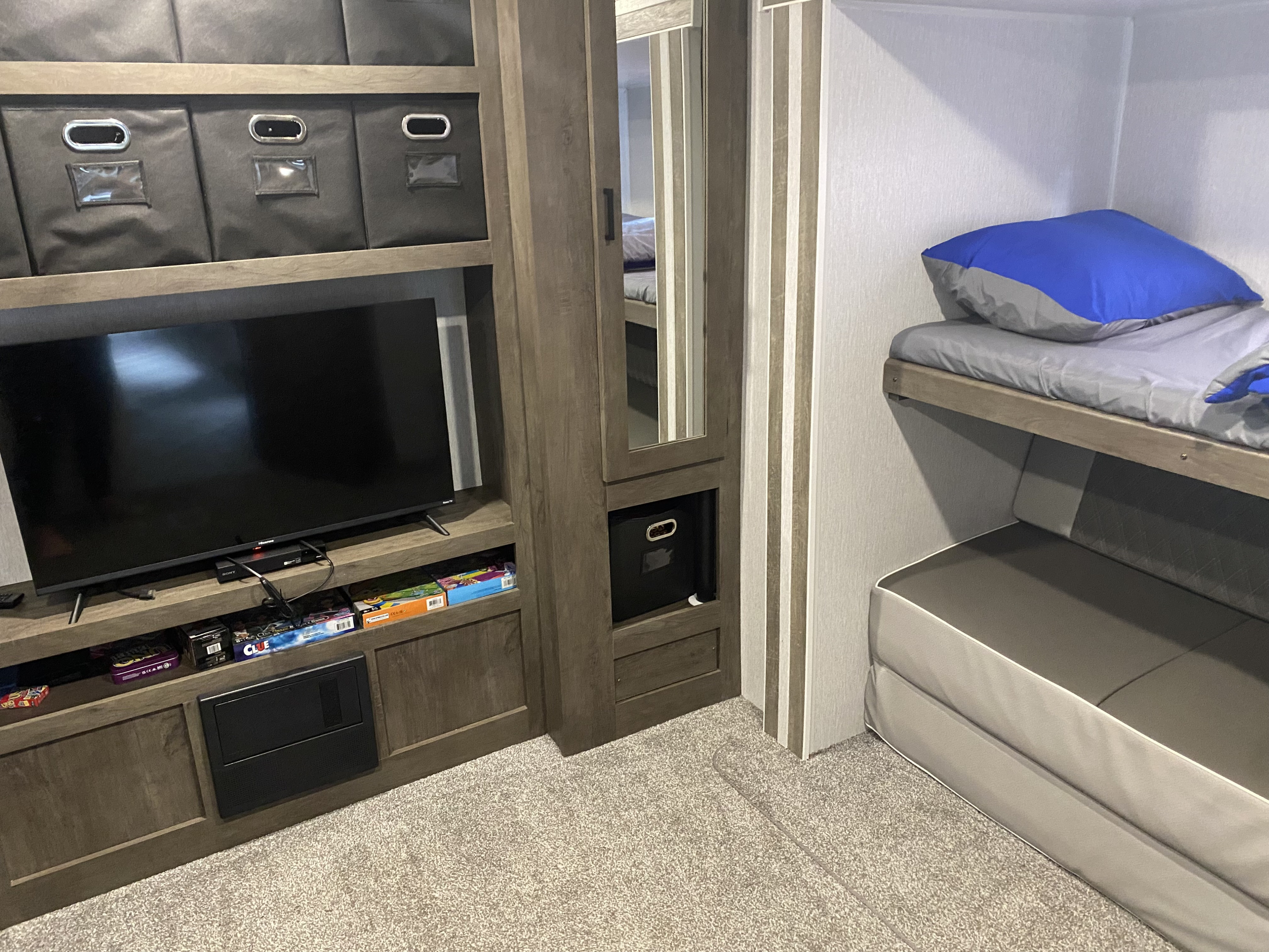 RV rental interior: a compact living space with entertainment unit, fabric storage bins, and bunk beds.. Forest River Wildwood 2022