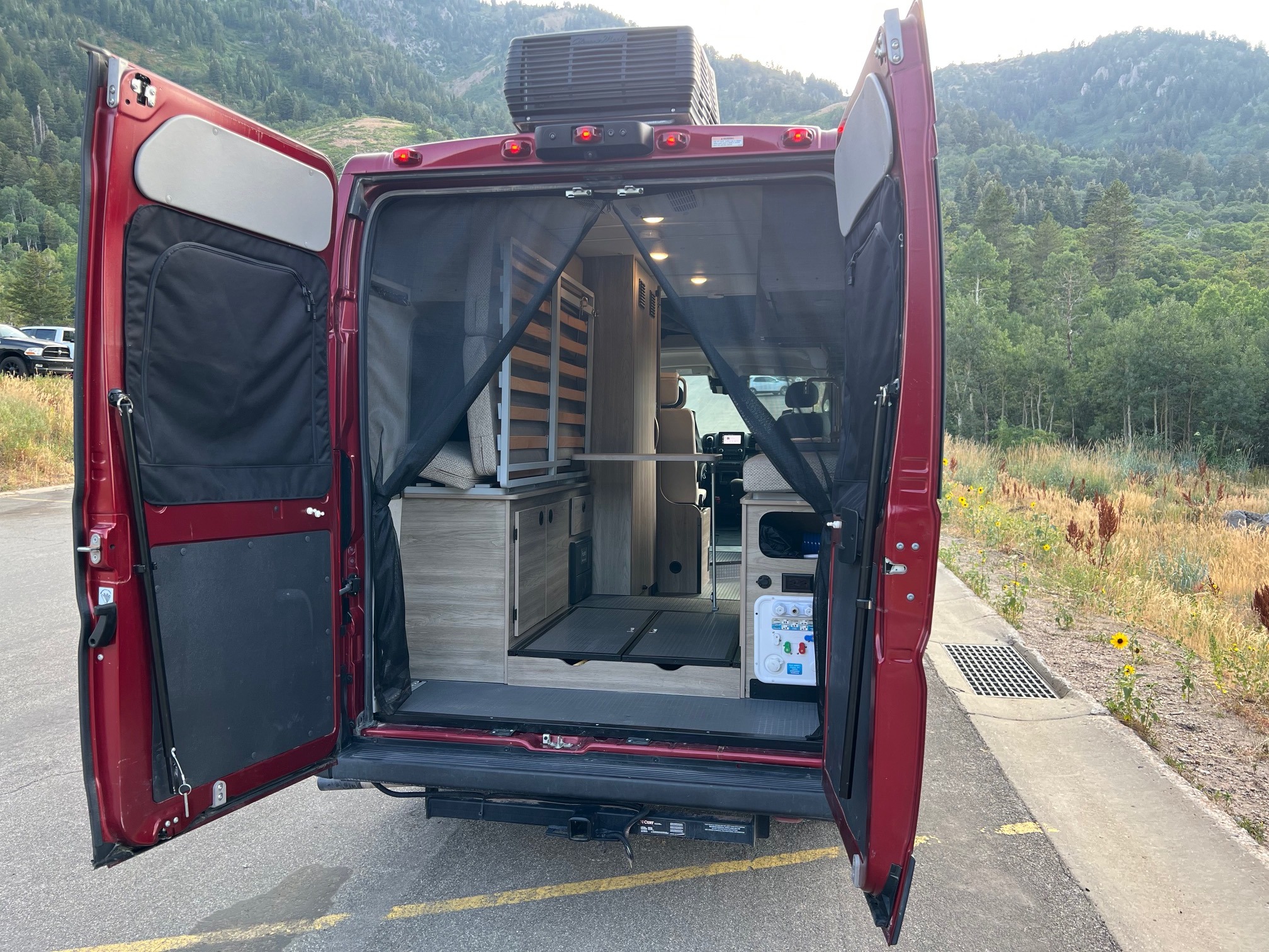 Inside an RV rental, the spacious camper van interior opens to a mountain view. Perfect for travel adventures.. Winnebago Solis 2023