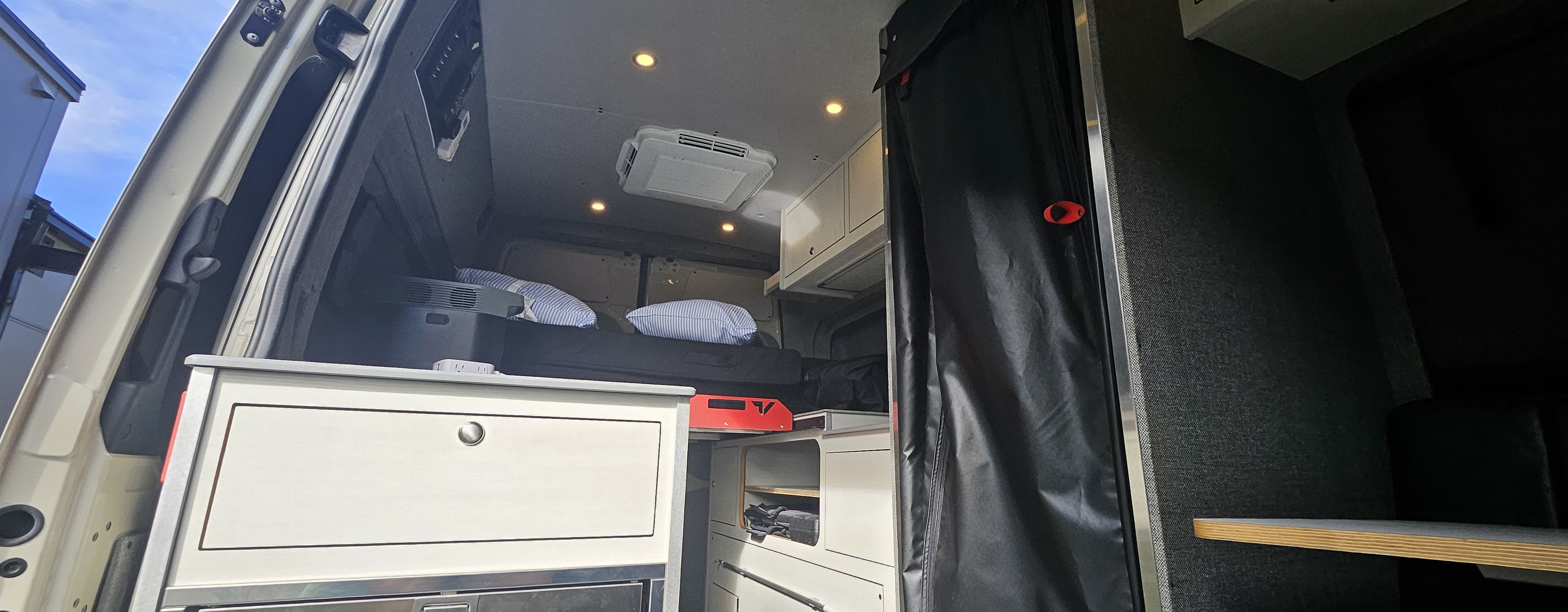 Inside this RV rental: a comfy bed, overhead AC unit, and kitchen storage, perfect for your next road trip.. Mercedes-Benz Sprinter 2500 AWD High Roof 2024