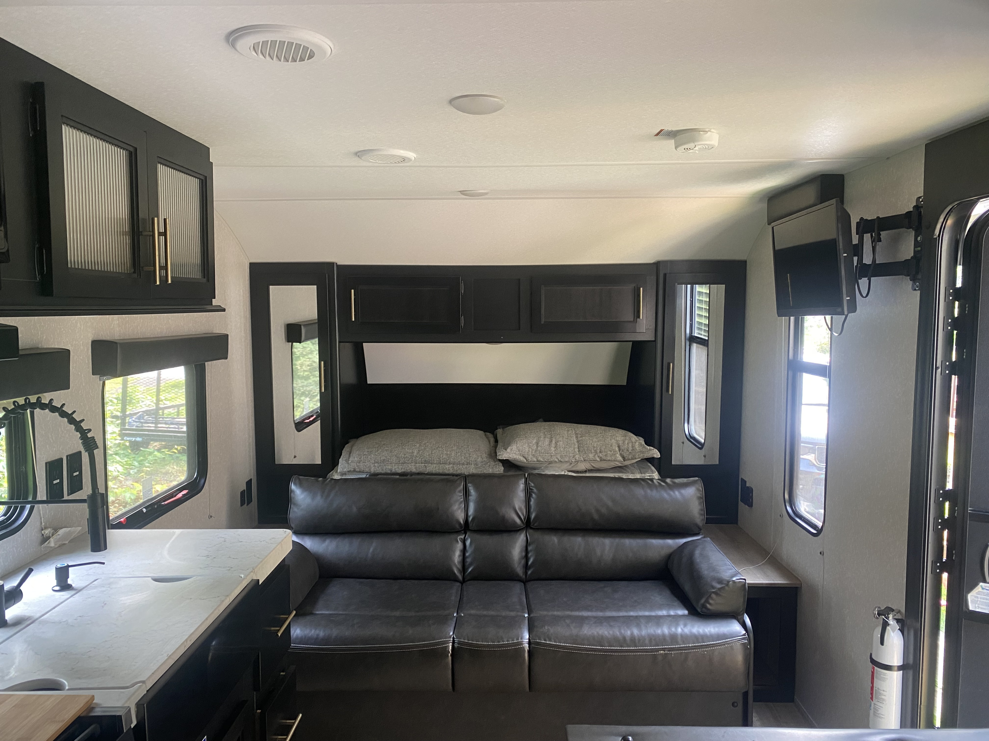 Inside a modern RV rental: a compact living space featuring a convertible sofa, kitchen, and ample overhead storage.. Forest River Cherokee Grey Wolf Special Edition 2022