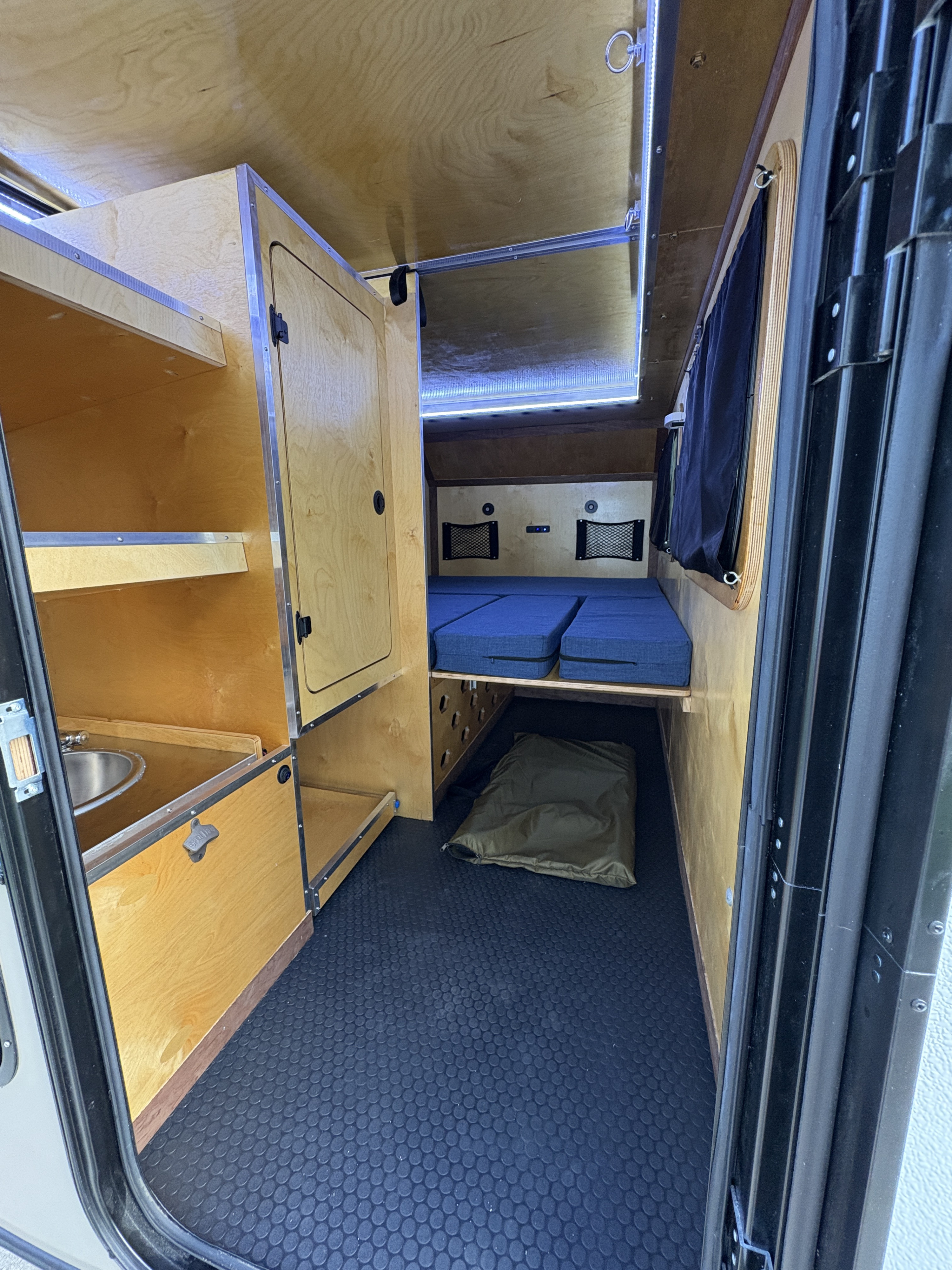 Cozy rv rental interior: light wood, blue sleeping cushions, compact sink, and storage for adventurous trips.. Venture XL Off road 2025