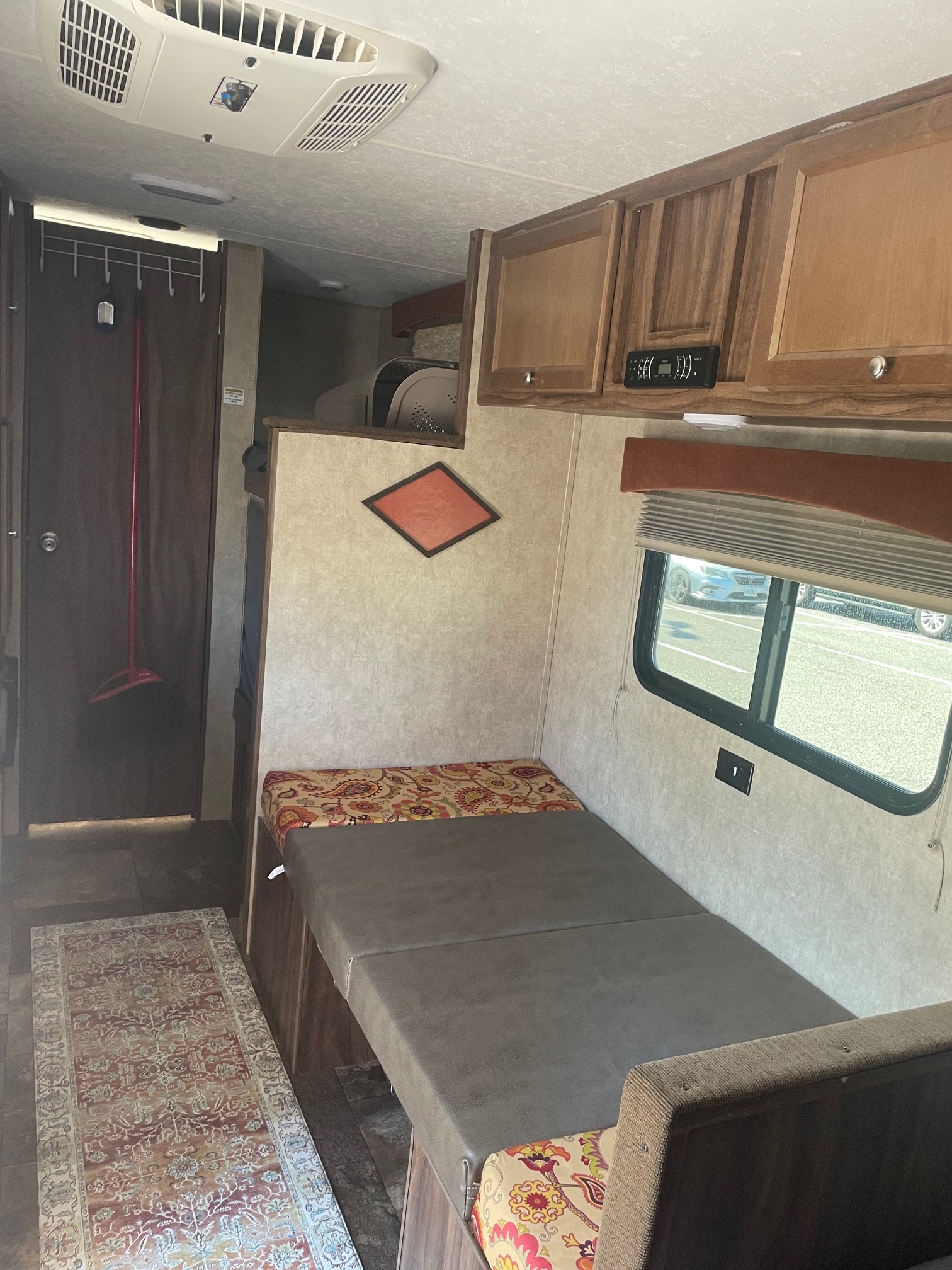 A cozy RV rental interior, featuring a convertible bed/seating area, overhead cabinets, and AC for your travels.. Forest River 2017 forest river clipper towable 17bh 2017