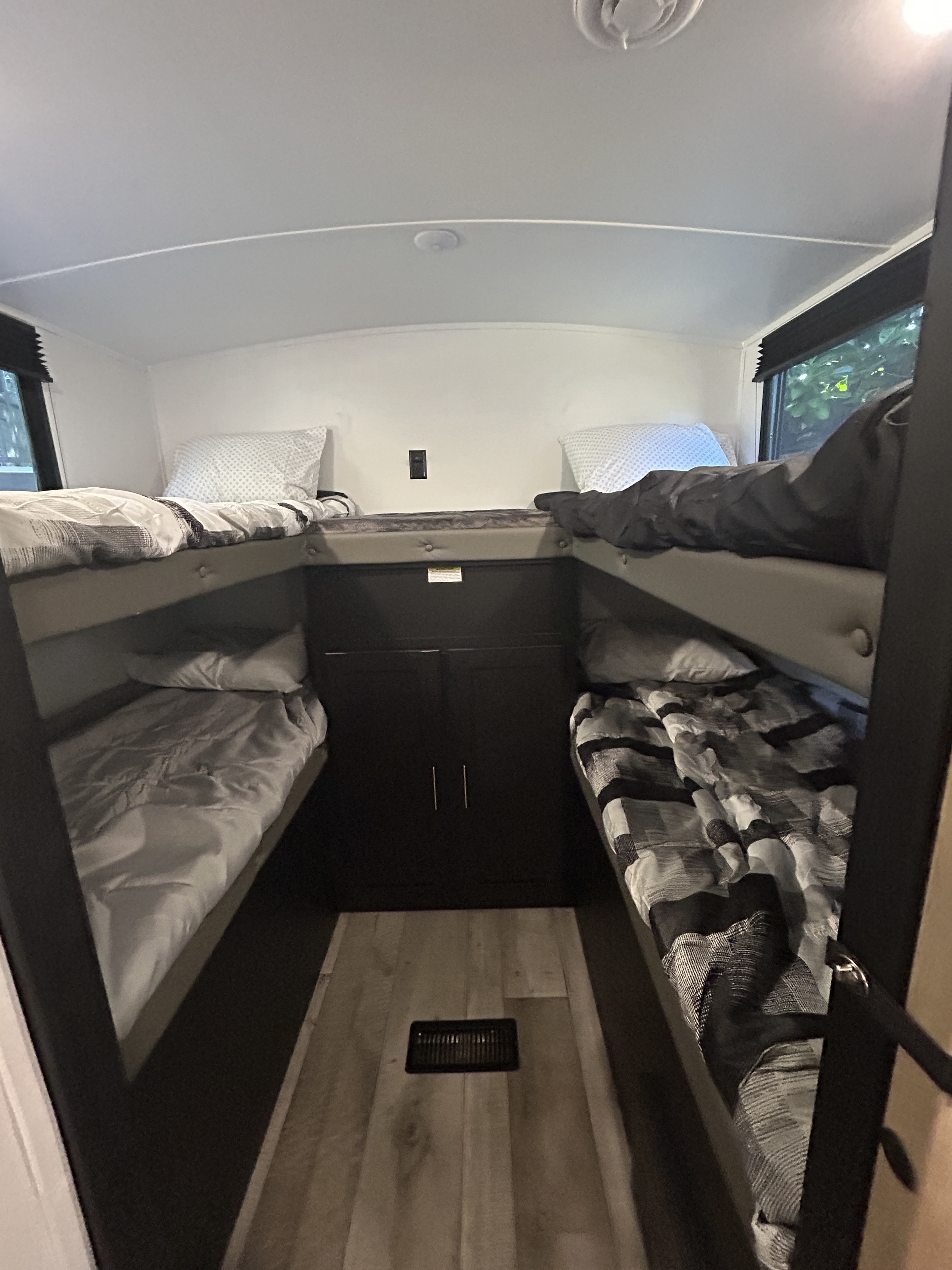 RV rental bunk room with four beds (two upper, two lower), central storage, and windows on each side.. Keystone RV Springdale 2022