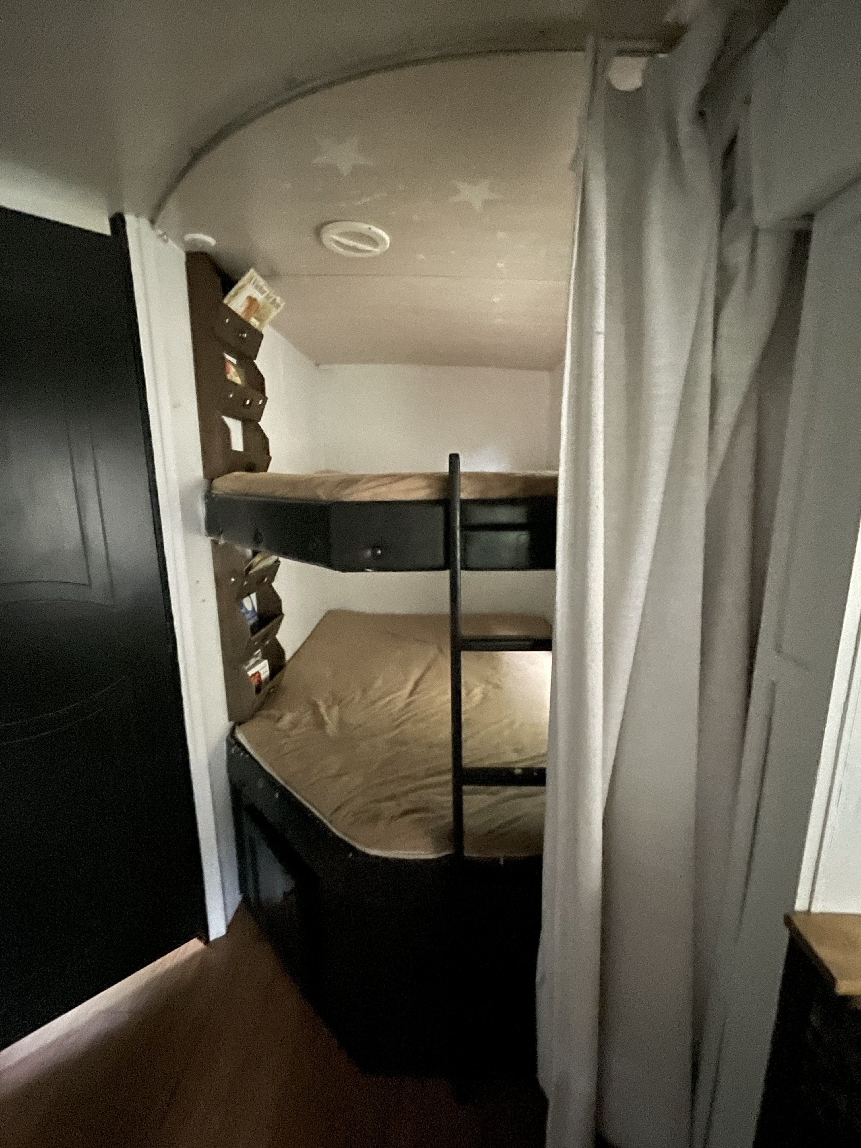 Inside an RV rental: Two bunk beds with a ladder, built-in shelving, and star-decorated ceiling, providing a compact sleep area.. Heartland RVs Wilderness 2018