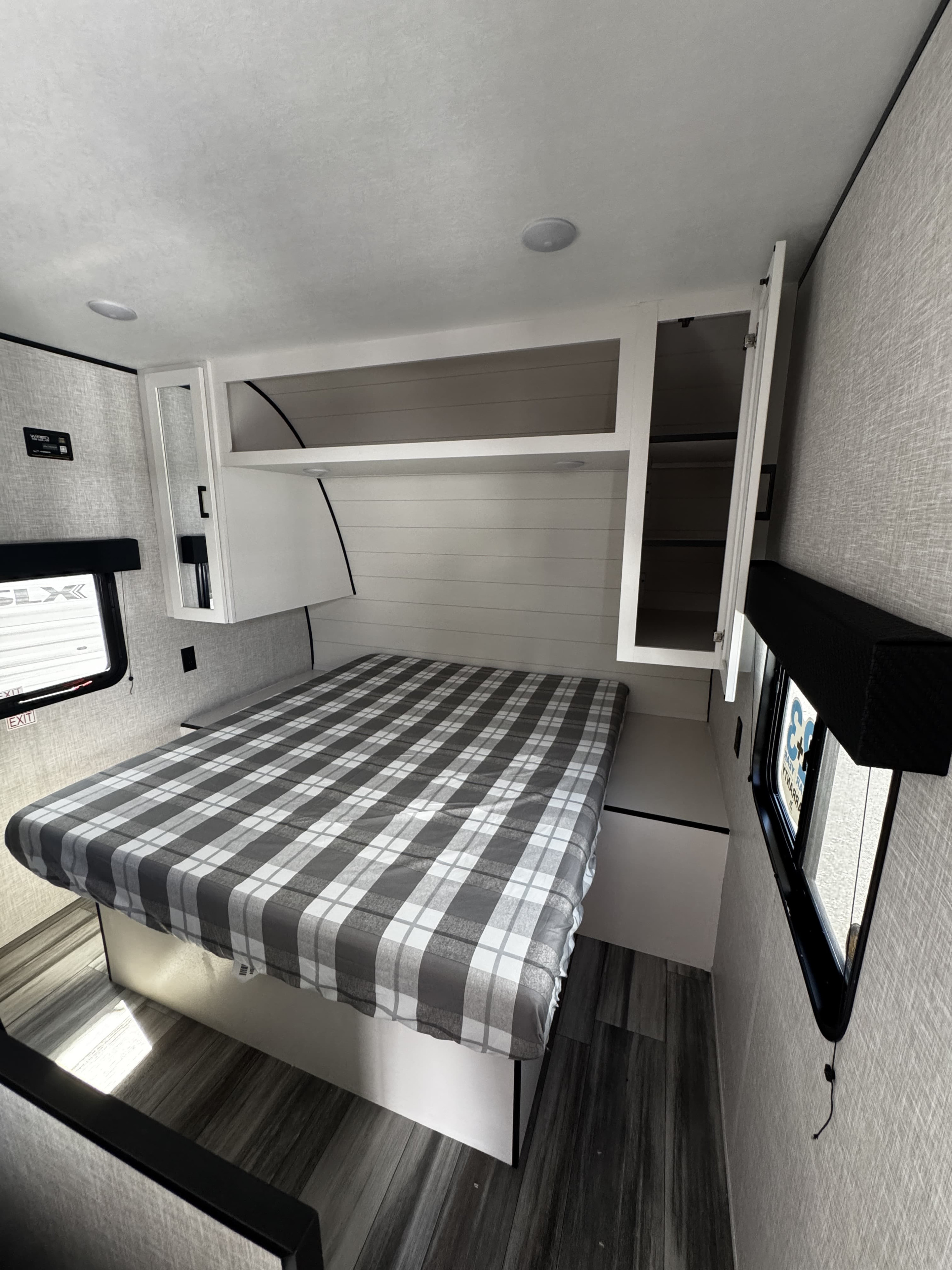 Modern RV rental bedroom with compact design, plaid bed, and overhead storage cabinets. Ideal for travel.. JAYCO 260BH JAY FLIGHT SLX TT 2025