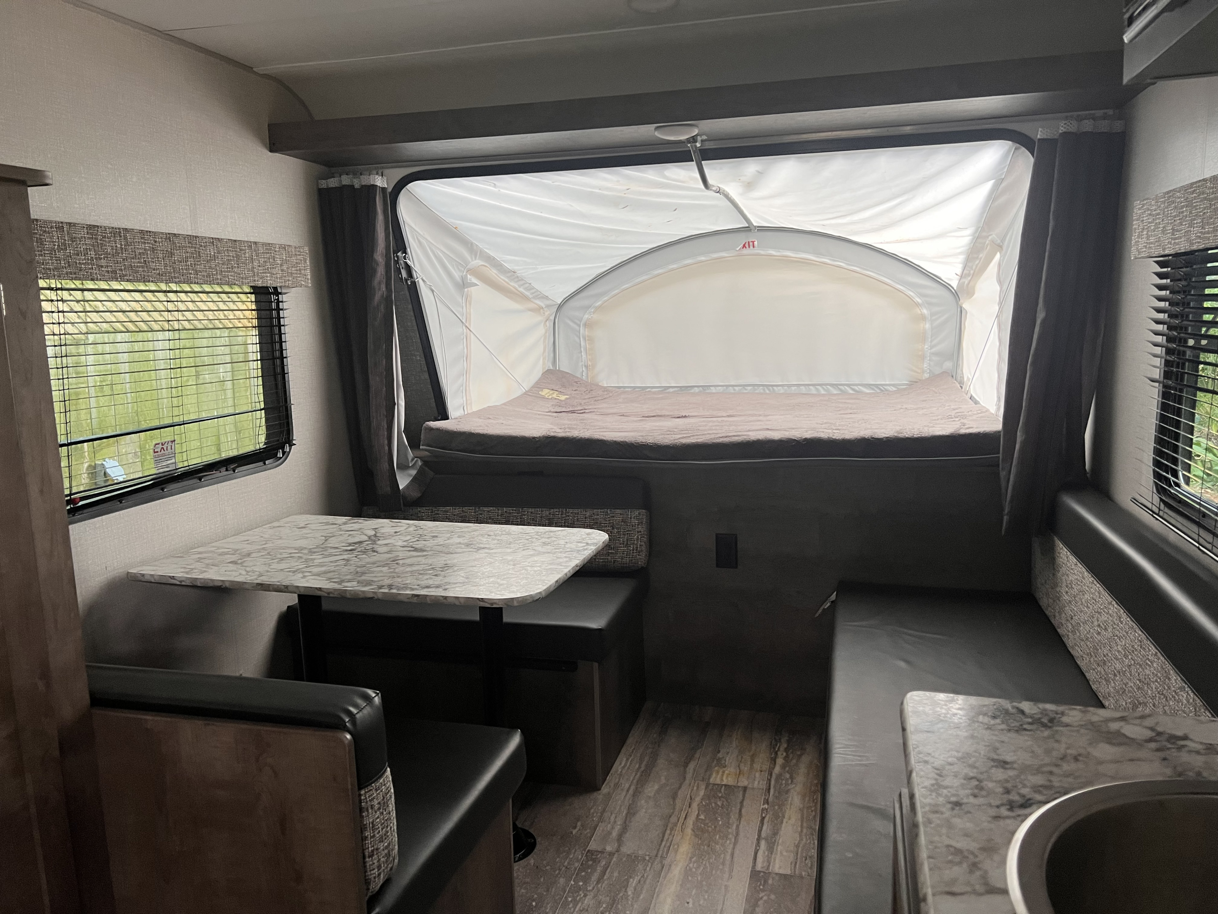 Cozy rv rental interior featuring a pop-out bed, dining booth, and compact living space. Ideal for travel adventures.. KZ 160RBT 2021