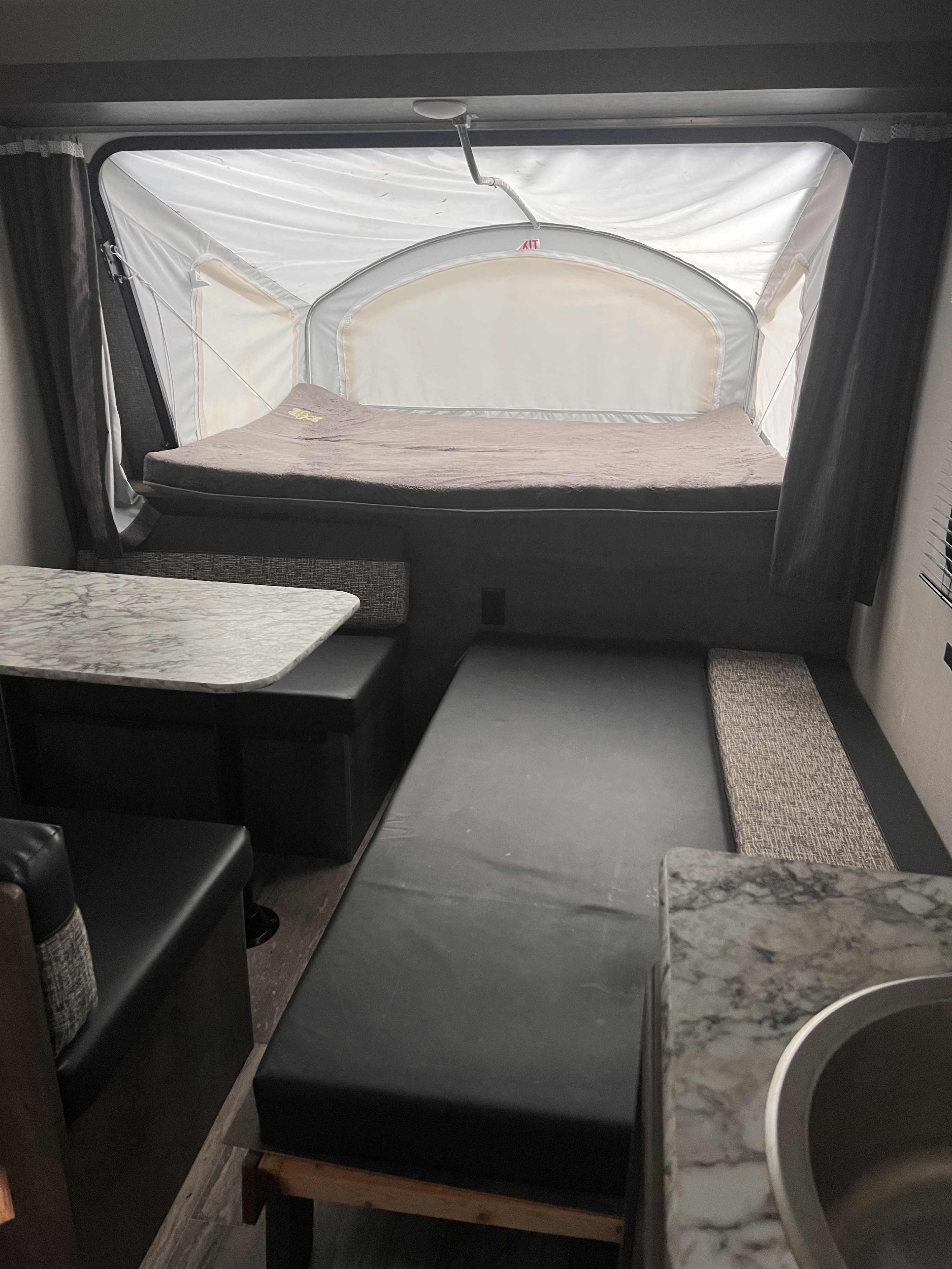Cozy RV rental interior with pop-out bed, convertible dinette, and sink, designed for compact living.. KZ 160RBT 2021