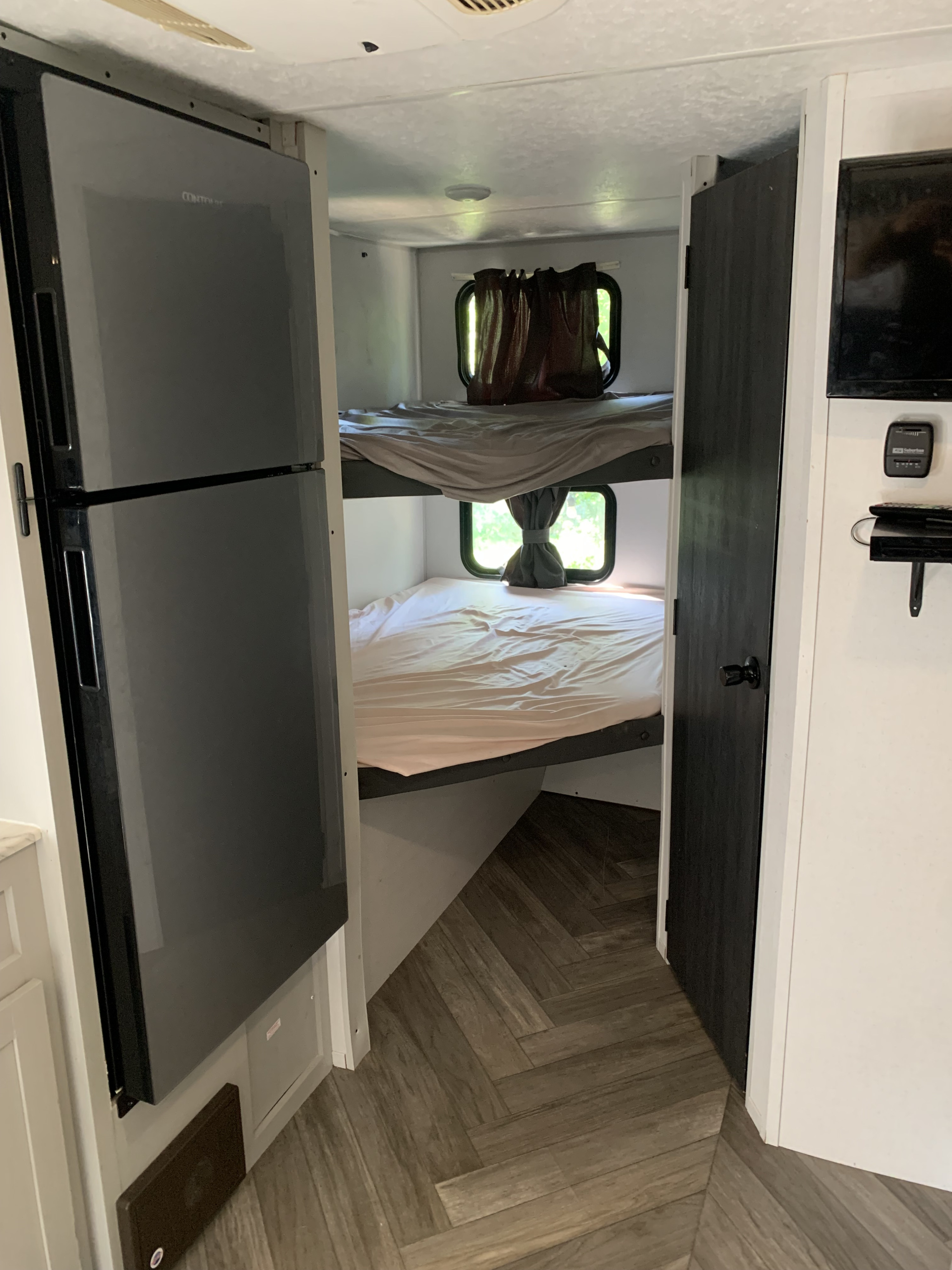 RV rental interior with comfortable bunk beds, dark refrigerator, and herringbone wood-look floor.. Forest River Salem FSX 2021