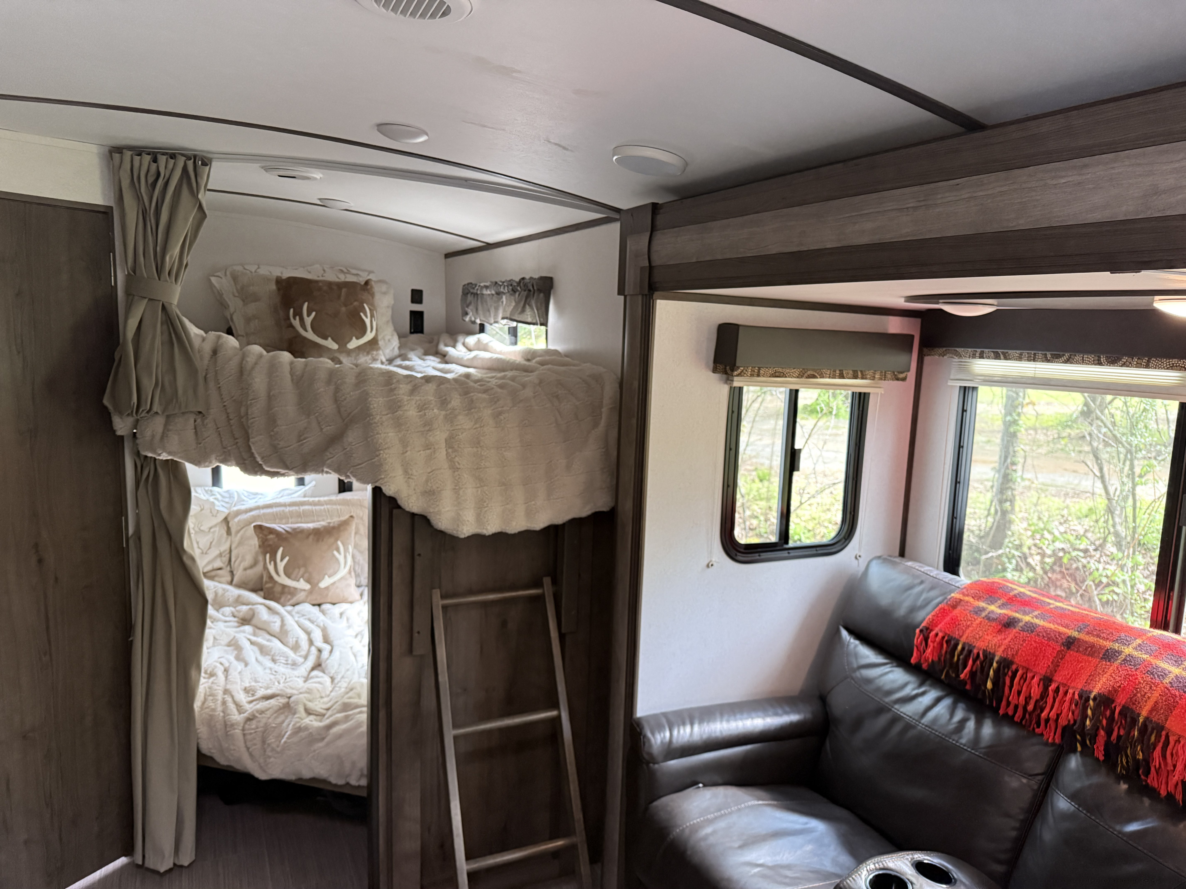 RV rental bunk area: two beds with cream bedding, antler pillows, ladder. Keystone RV Passport Grand Touring 2020