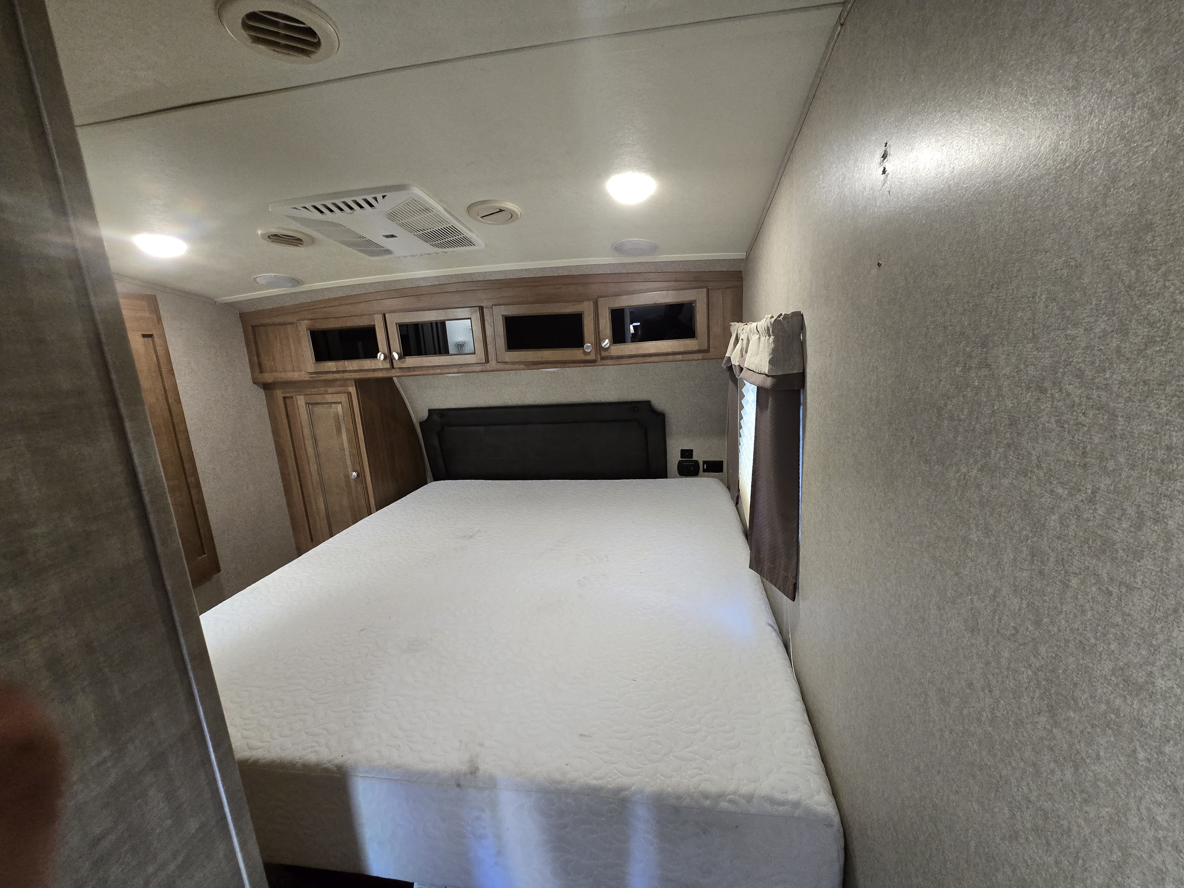 RV rental bedroom: bright interior with large bed, overhead cabinets, wardrobe, and ceiling vents.. Forest River Rockwood Signature Ultra Lite 2018