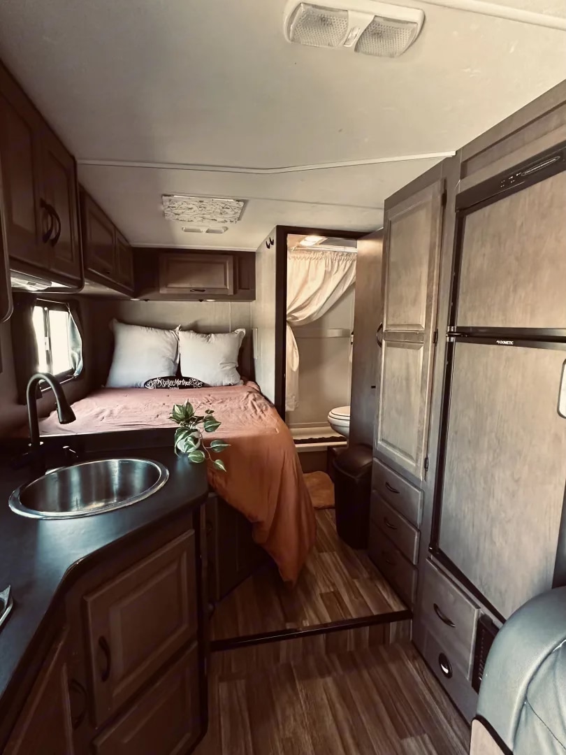 Cozy RV rental interior, showcasing kitchen, bed, and bathroom area. Your compact home on wheels.. Thor Majestic 2019