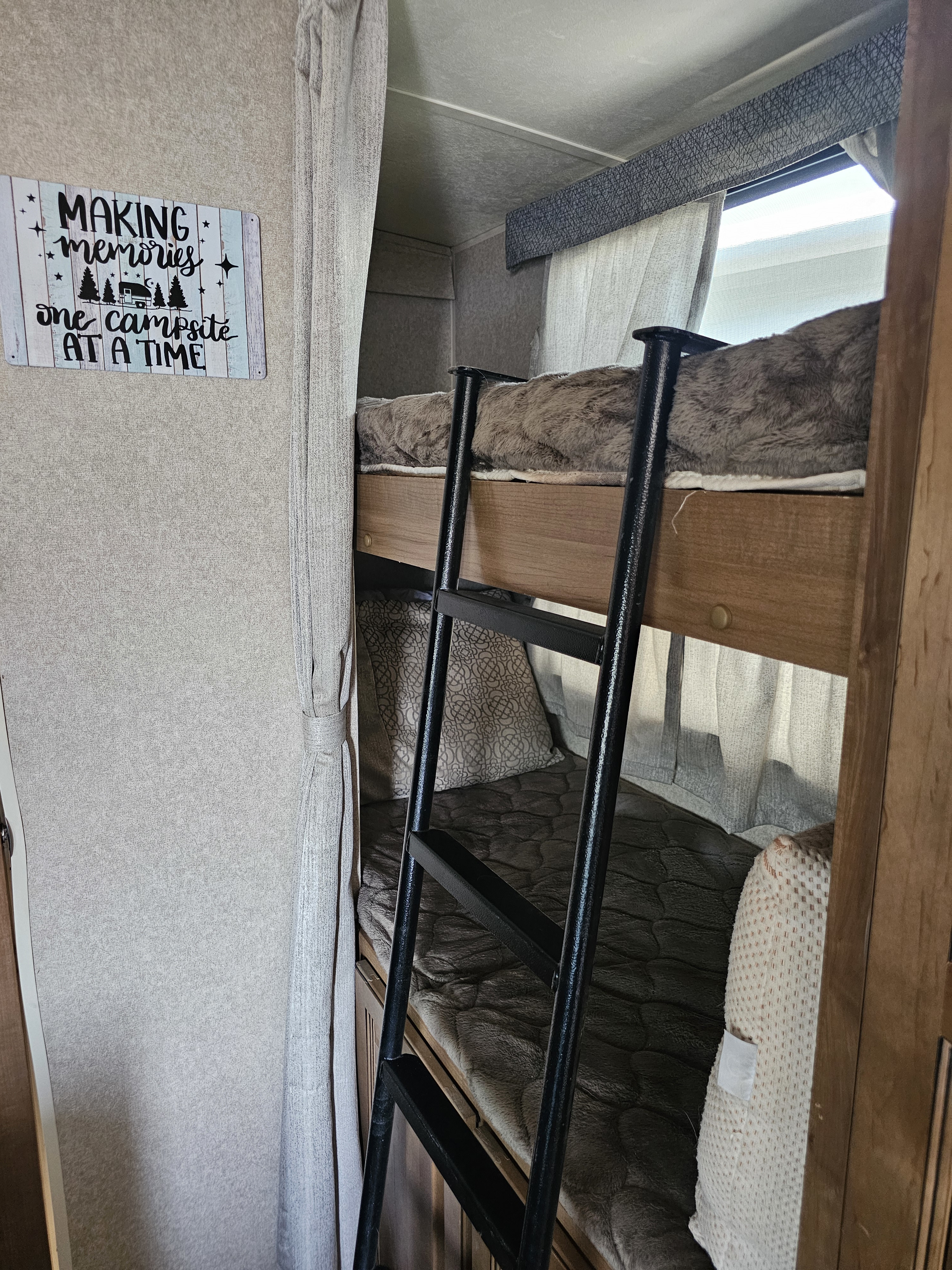 Cozy bunk beds in an RV rental, featuring a "Making memories" sign and soft bedding.. Forest River Rockwood Mini Lite 2018