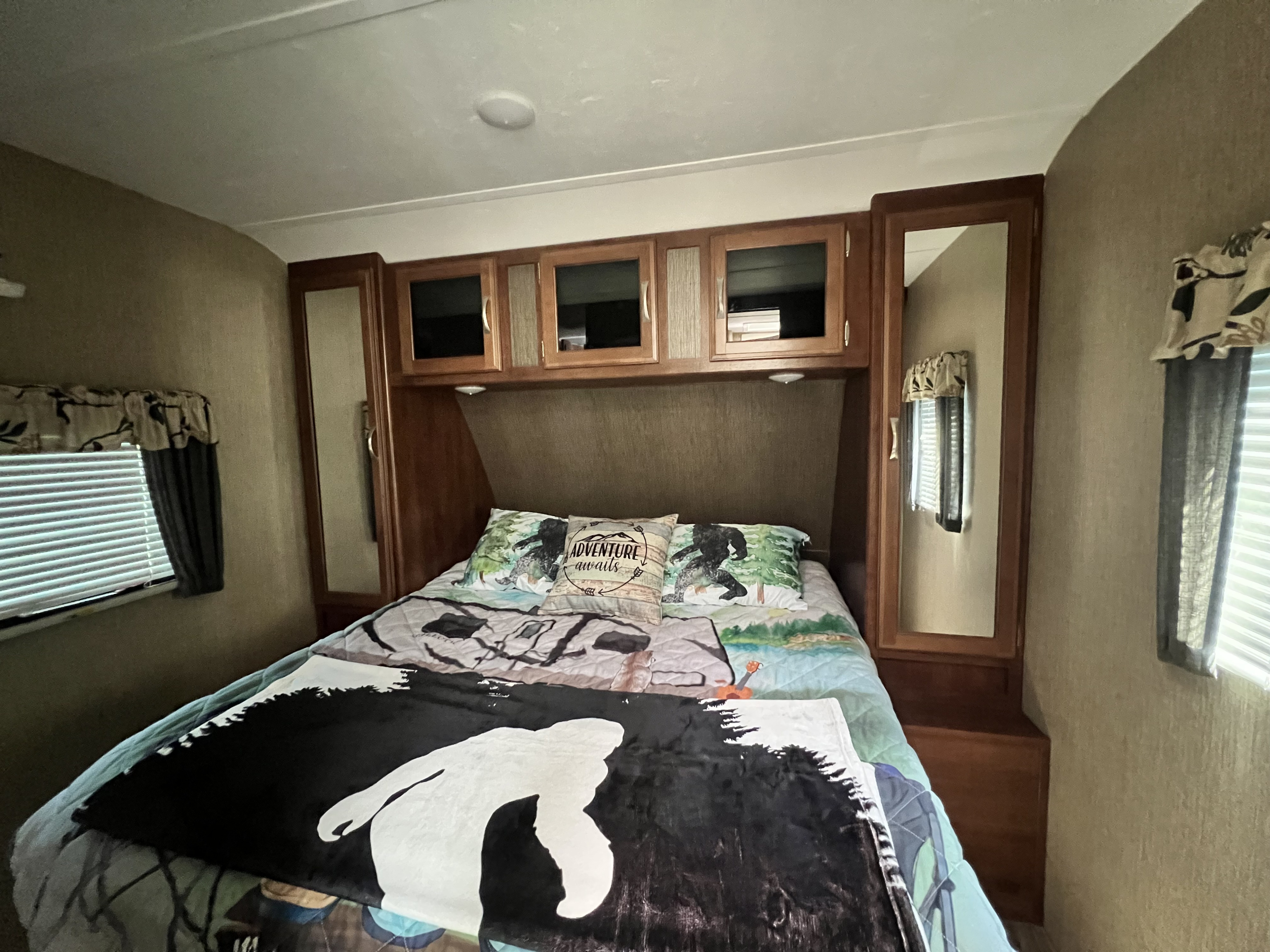 Cozy RV rental bedroom with Bigfoot bedding, overhead cabinets, and windows for your next adventure.. Keystone RV Passport Grand Touring 2017