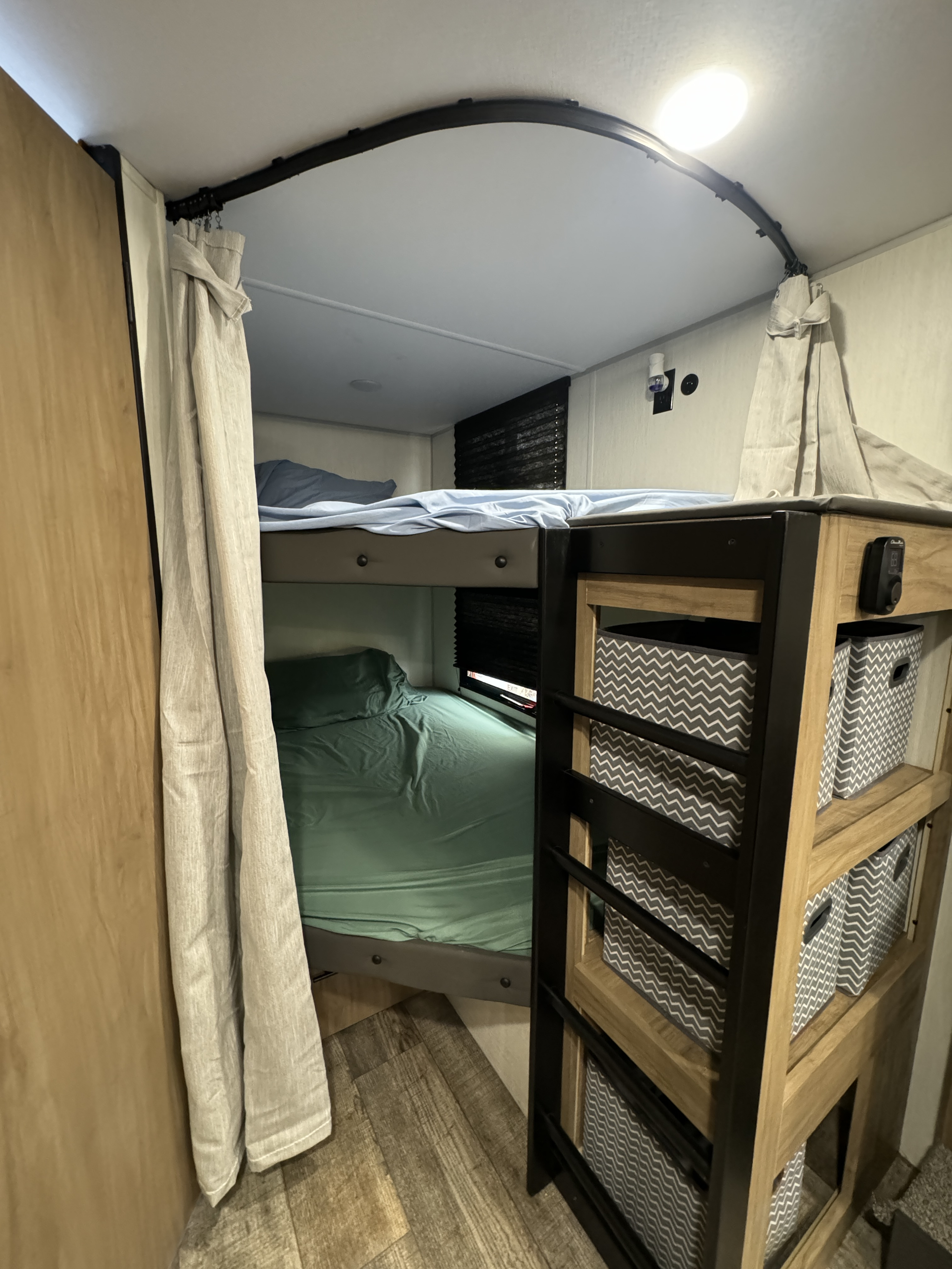 Cozy RV rental bunk beds with privacy curtains and storage bins, perfect for family travel.. Forest River Campsite reserve 26CJ 2025