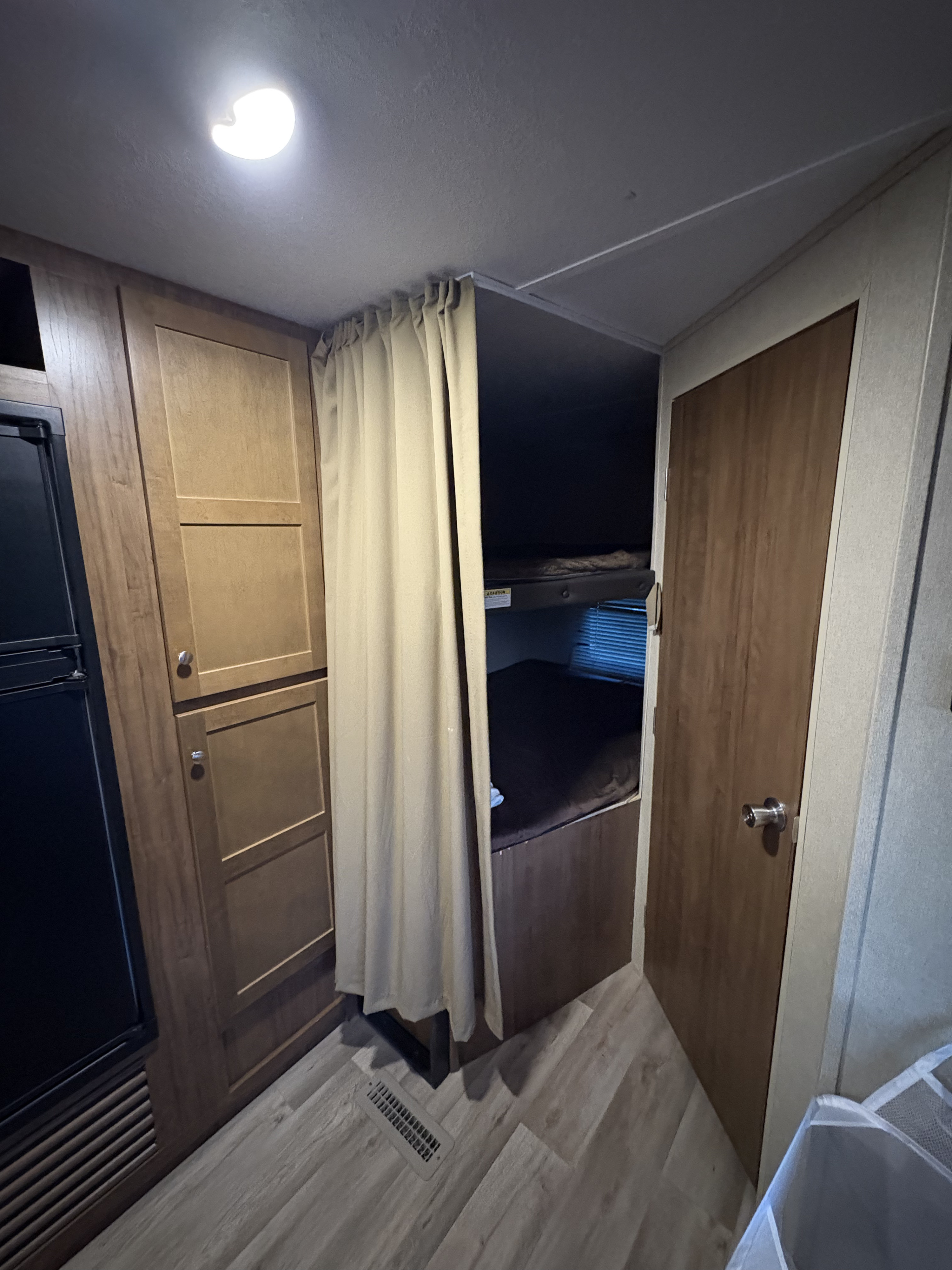Inside an RV rental: features include bunk beds with privacy curtain, fridge, and wood cabinets.. Aspen Trail Aspen Trail Trailer 2017