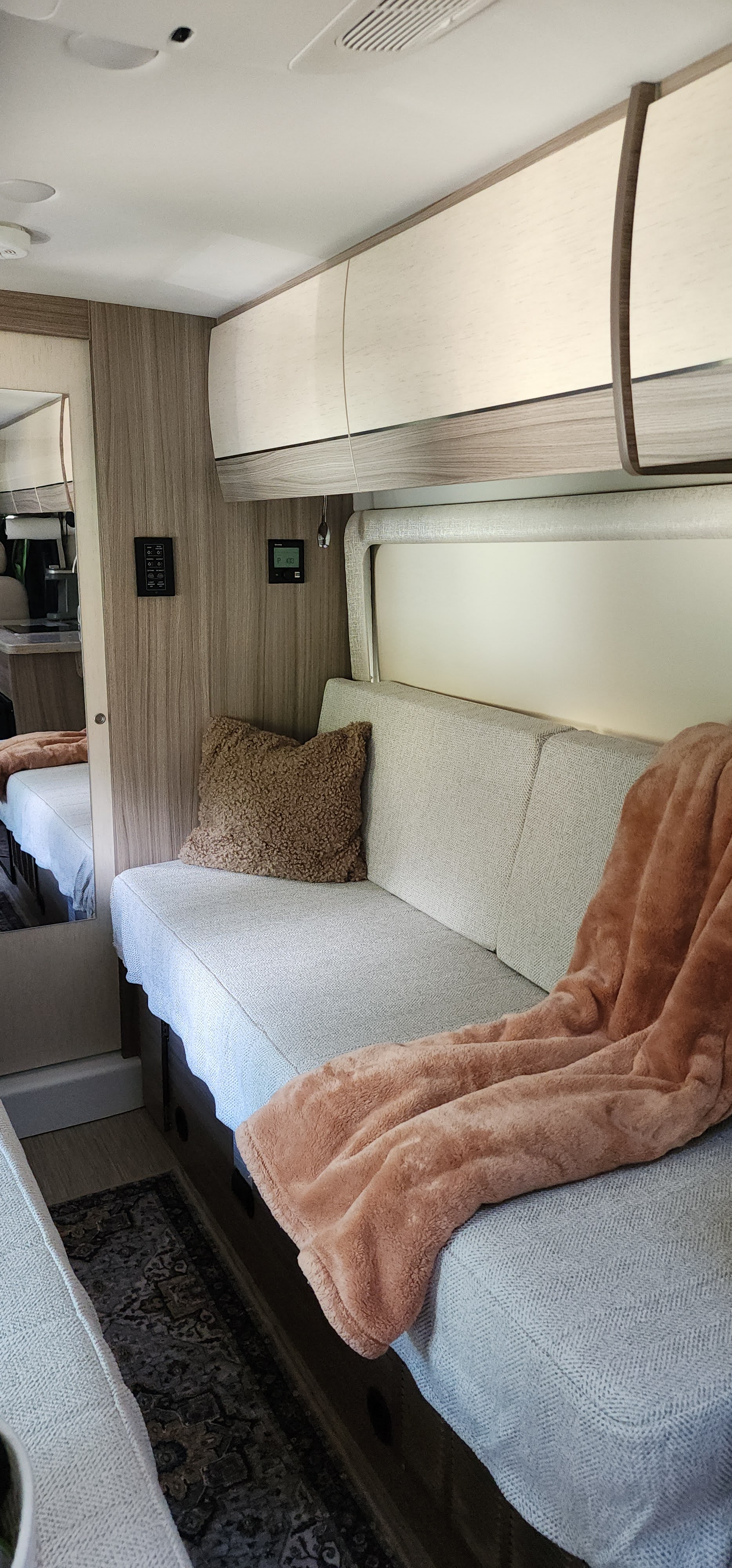 Step inside this cozy RV rental's living space, featuring a comfy bench seat with a soft blanket, and convenient overhead cabinets.. Entegra Coach Ethos 2024