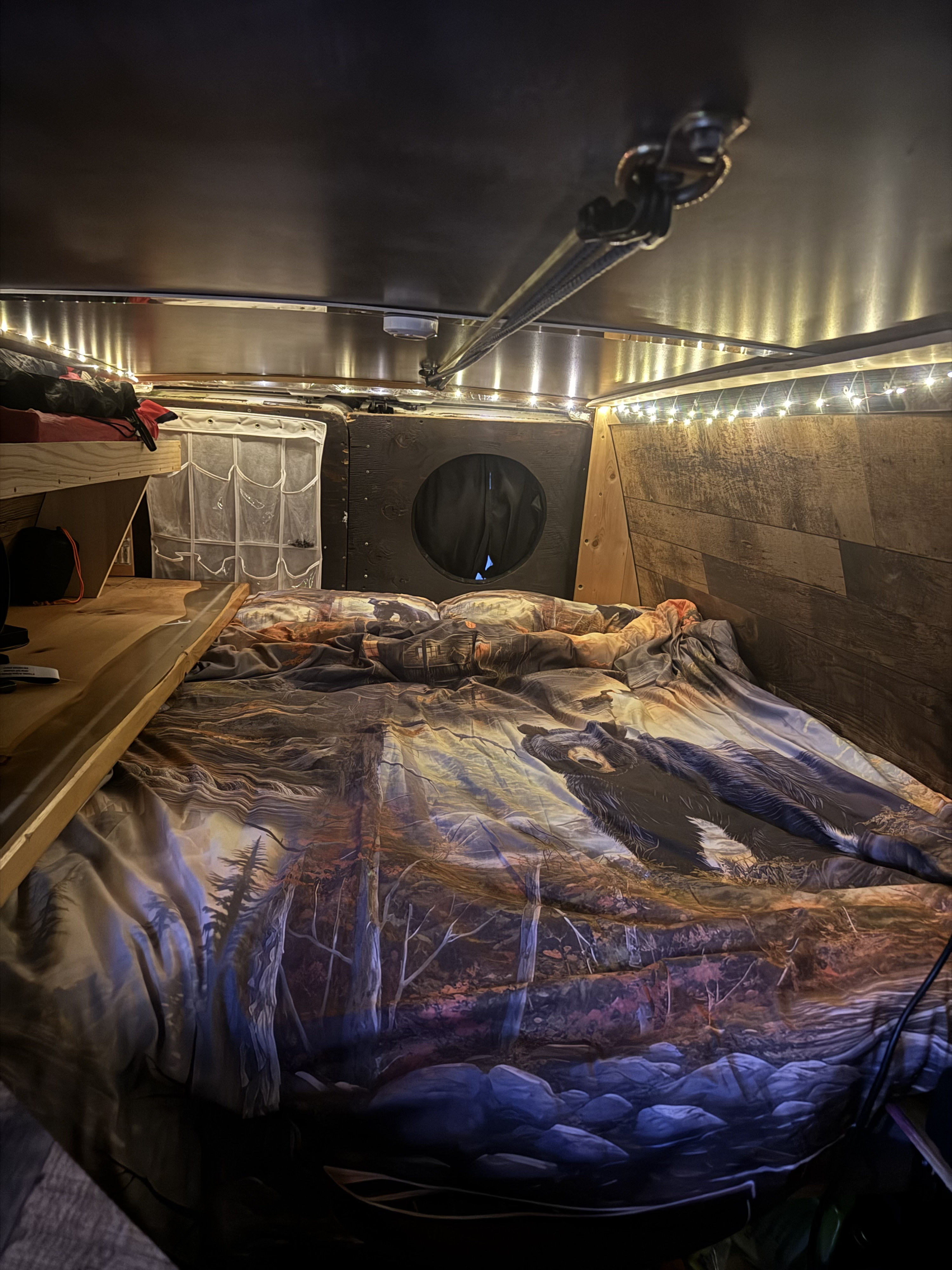 Cozy RV rental interior with a themed bed, wood panels, and warm fairy lights, offering a comfortable living space.. Ford E350 Box Van 2006