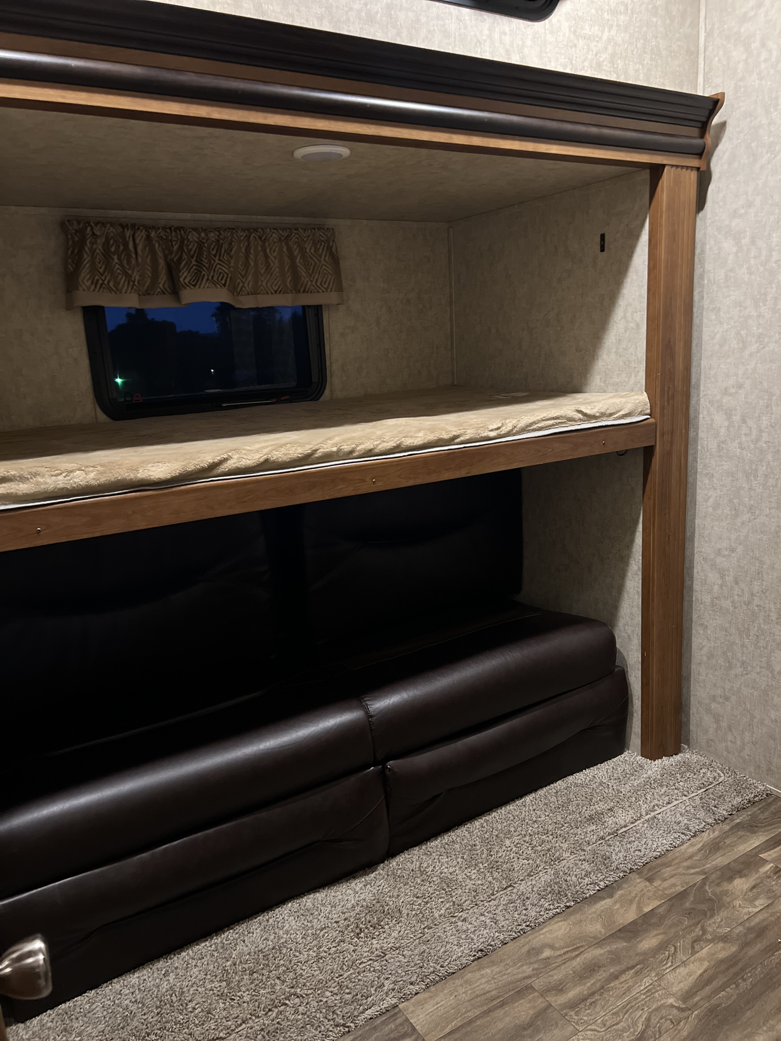 RV rental interior featuring a comfy bunk bed over a dark leather sofa, ideal for travel lodging.. Crusader Crusader Fifth Wheel 2016