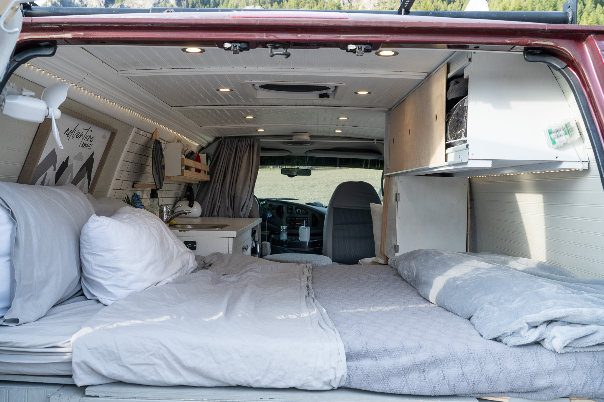 Cozy camper van interior, perfect for an RV rental adventure. Features a comfortable bed, mini-kitchen, and clever storage.. Ford Econoline 2006