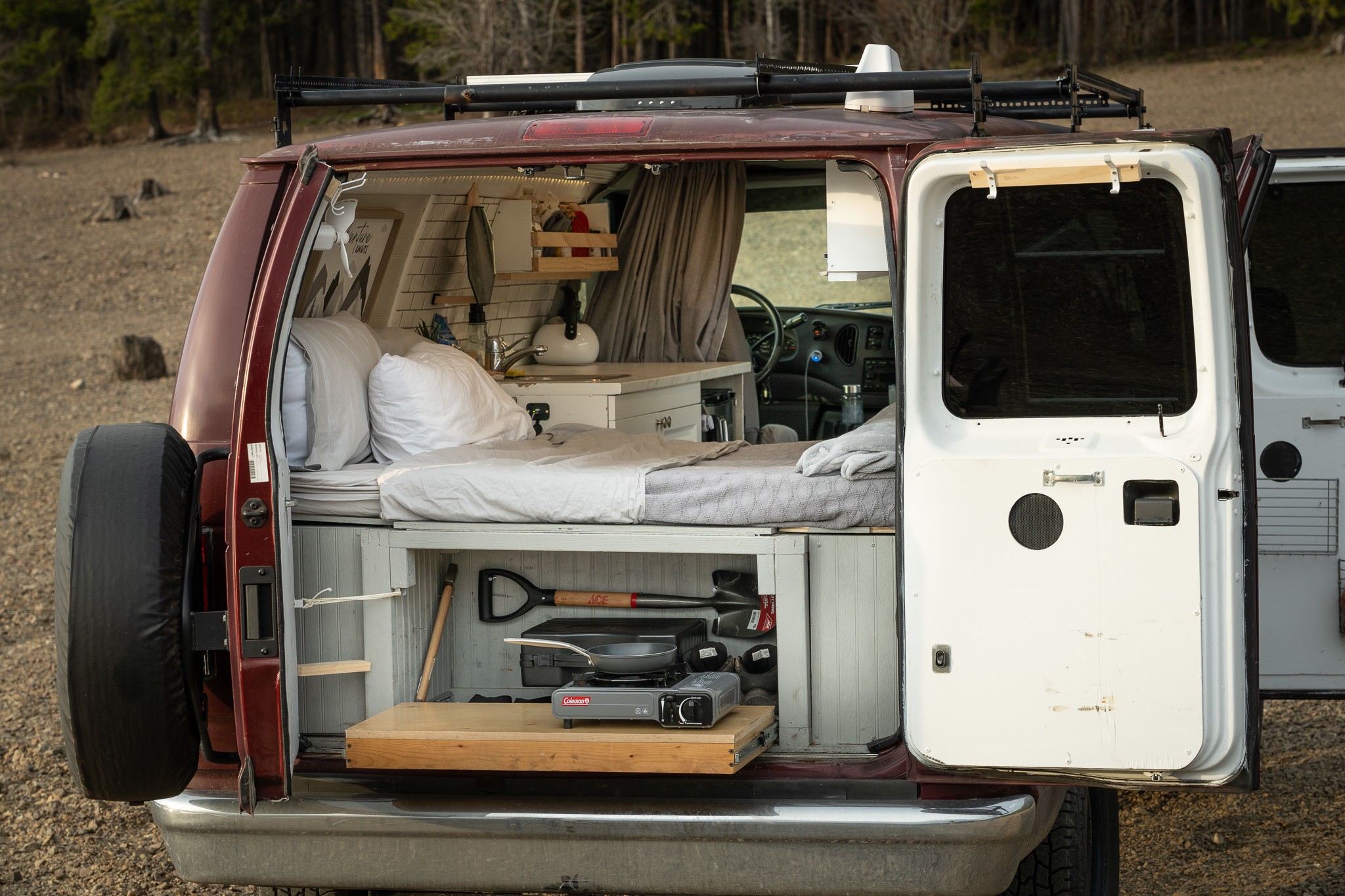 Inside this custom camper van, ideal for RV rental, a bed, kitchen, and pull-out stove are visible.. Ford Econoline 2006