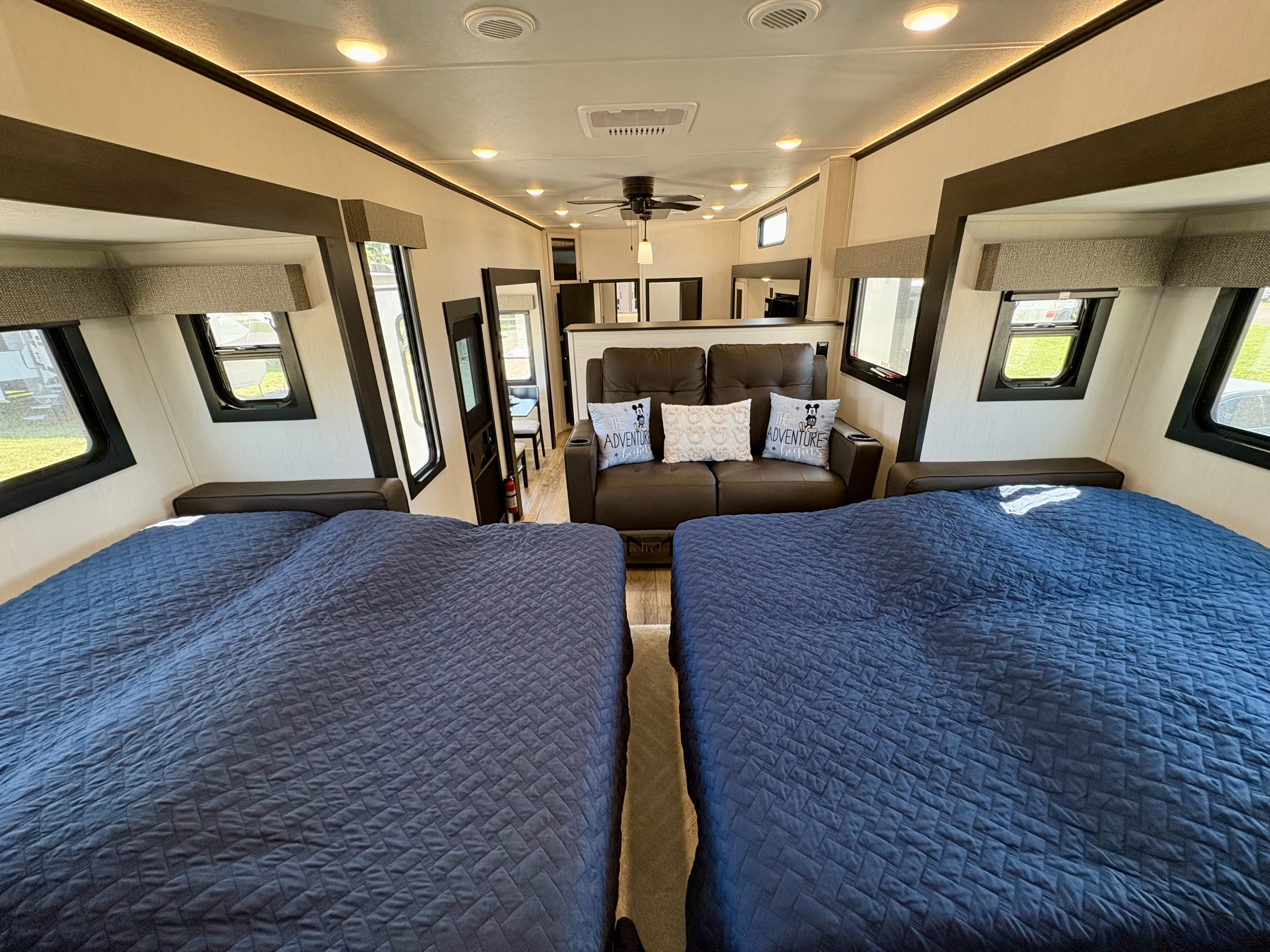 Spacious RV interior with two blue beds, a comfortable sofa, and bright lighting, ideal for your next rv rental adventure.. Forest River Sabre 2025
