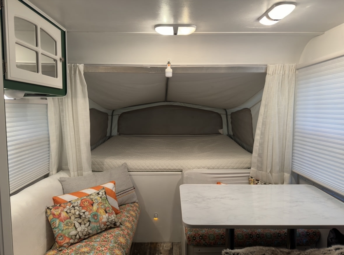 Cozy RV rental interior featuring a comfortable bed, dinette, and colorful seating.. Starcraft Antiqua 195 CK 2005