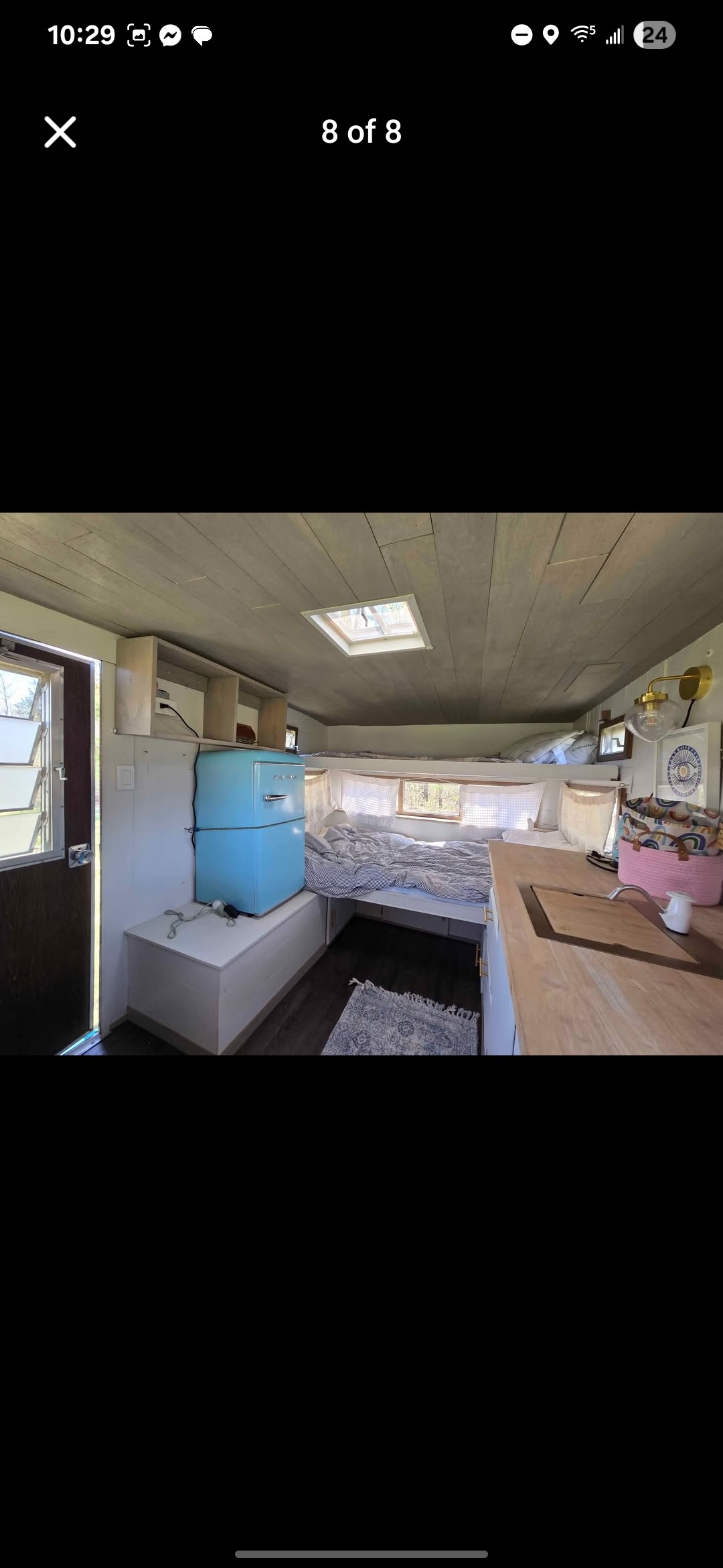 RV rental interior featuring a cozy bed, compact kitchen with wood counter, and a retro blue fridge.. Other Other 1973