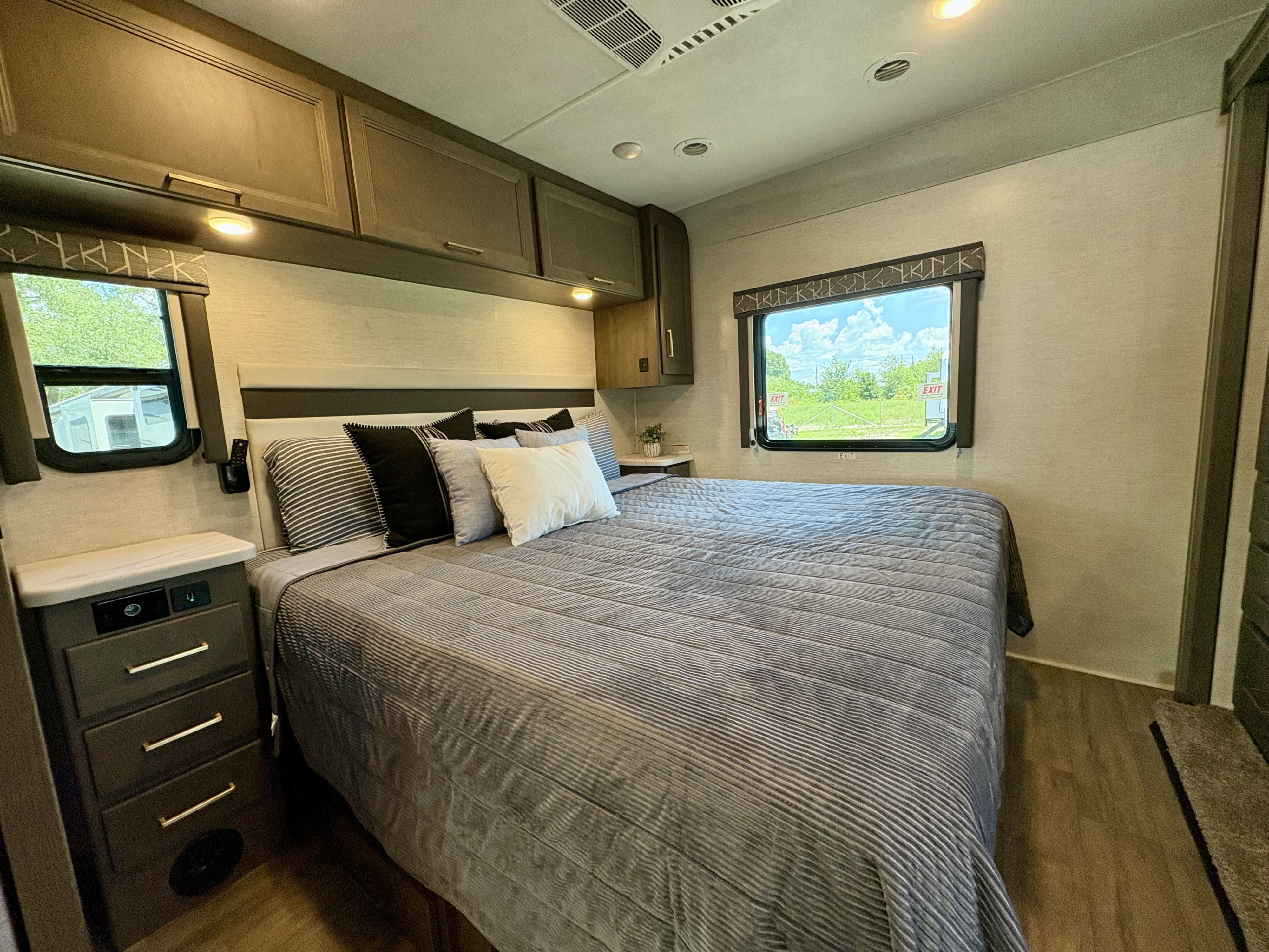 Cozy RV rental bedroom featuring a comfortable bed, ample storage, and windows with natural light.. Thor ACE 2024